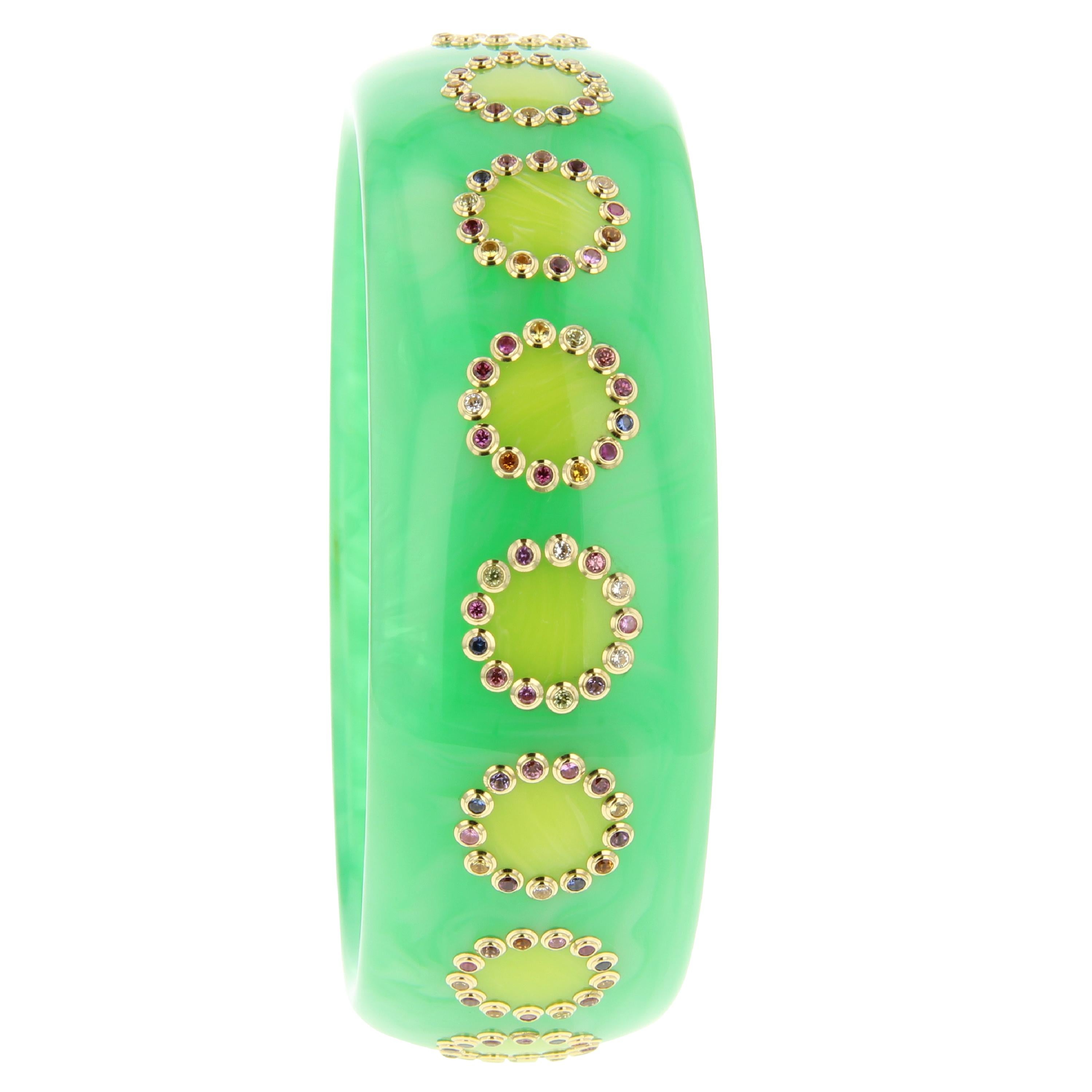 This cheerful and bright vintage bakelite bangle by Mark Davis was made from a lovely medium green bakelite with greenish-yellow disks inlaid around the circumference. Each inlaid disk is framed with a border of individually set, lively gems in a