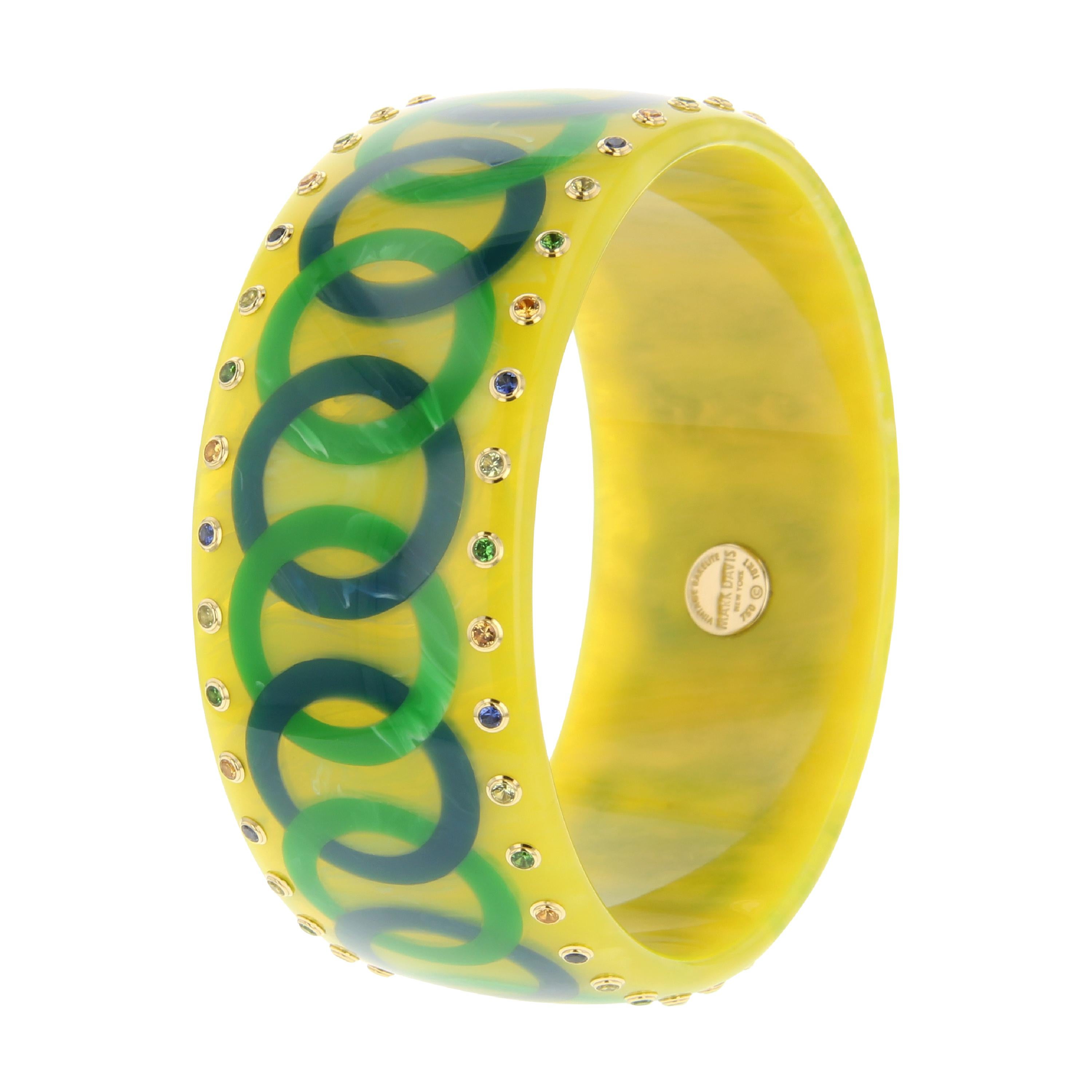 This vintage yellow bakelite bangle by Mark Davis was created with a pattern of interlocking blue and green bakelite links that circle the bangle in an endless chain. The process of inlaying the bangle perfectly was technically challenging and the