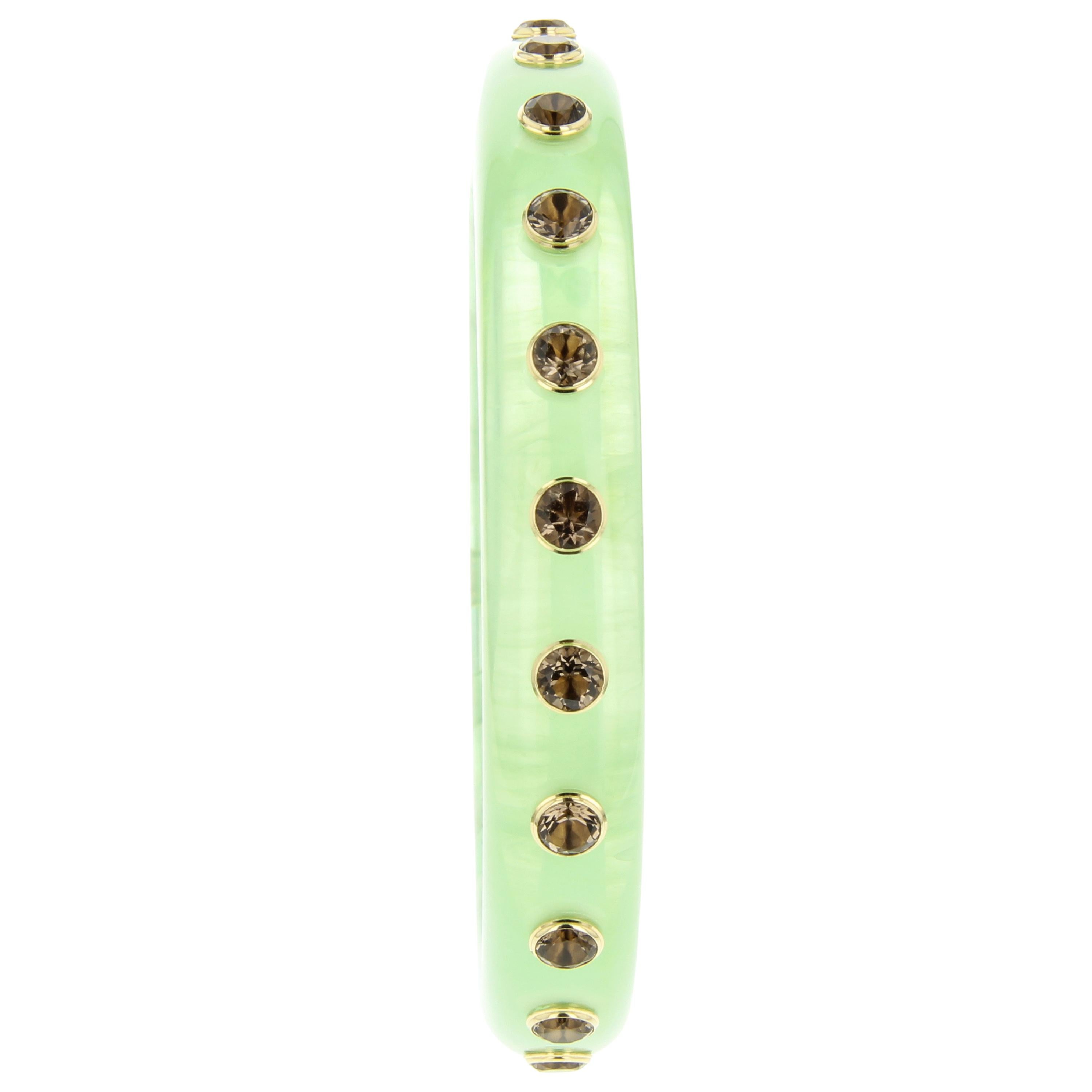 This beautiful bangle was created by Mark Davis in an unusual, highly translucent, soft green, vintage bakelite. Twenty-two evenly spaced smoky quartz in 18k yellow gold bezels encircle the bangle. The surprisingly versatile and unusual color pairs