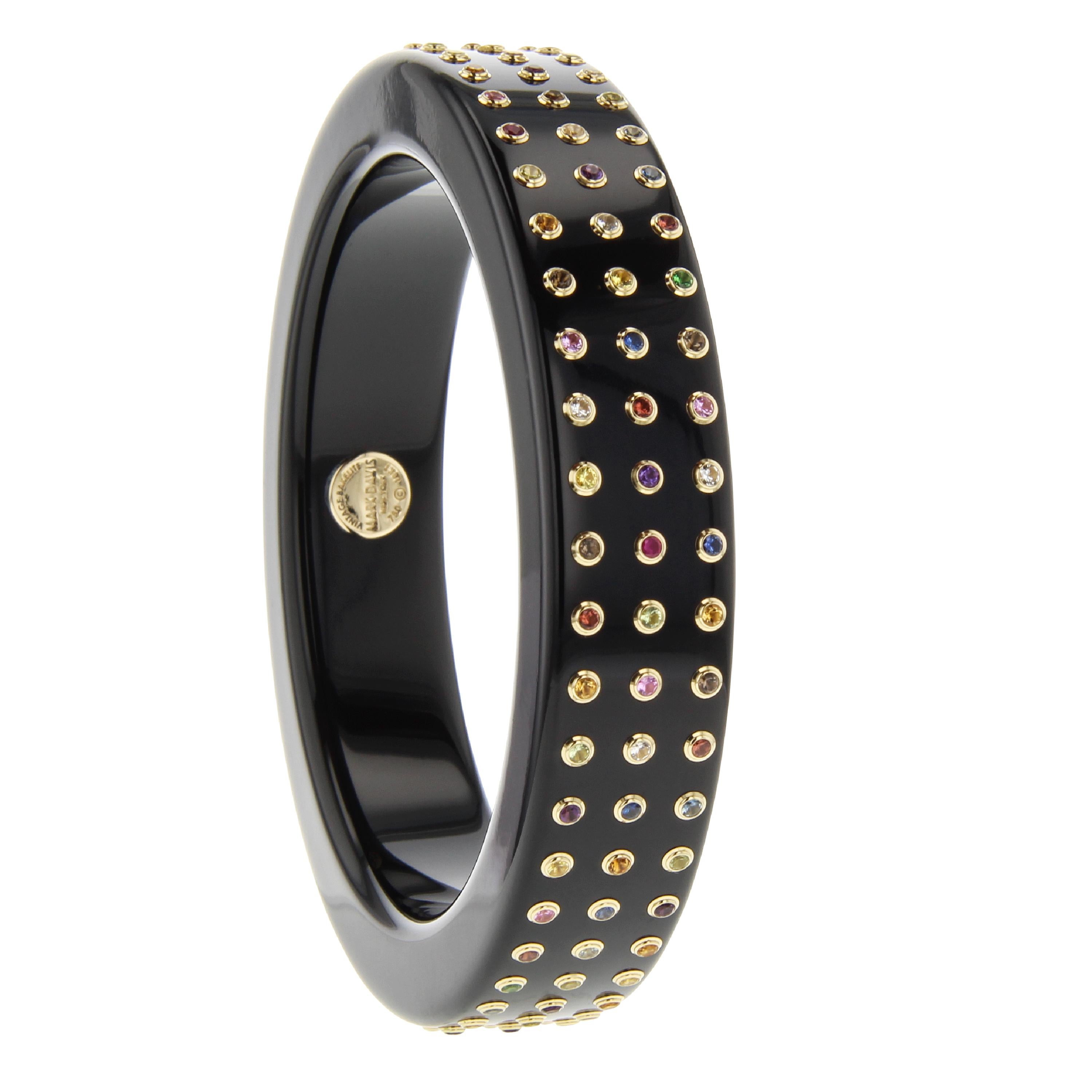 This Mark Davis bangle is made from solid black, vintage bakelite. Although round in shape, it has a square, almost chunky feel. The linear shape is further echoed by three rows of perfectly spaced gemstones all mounted in individual 18k yellow gold
