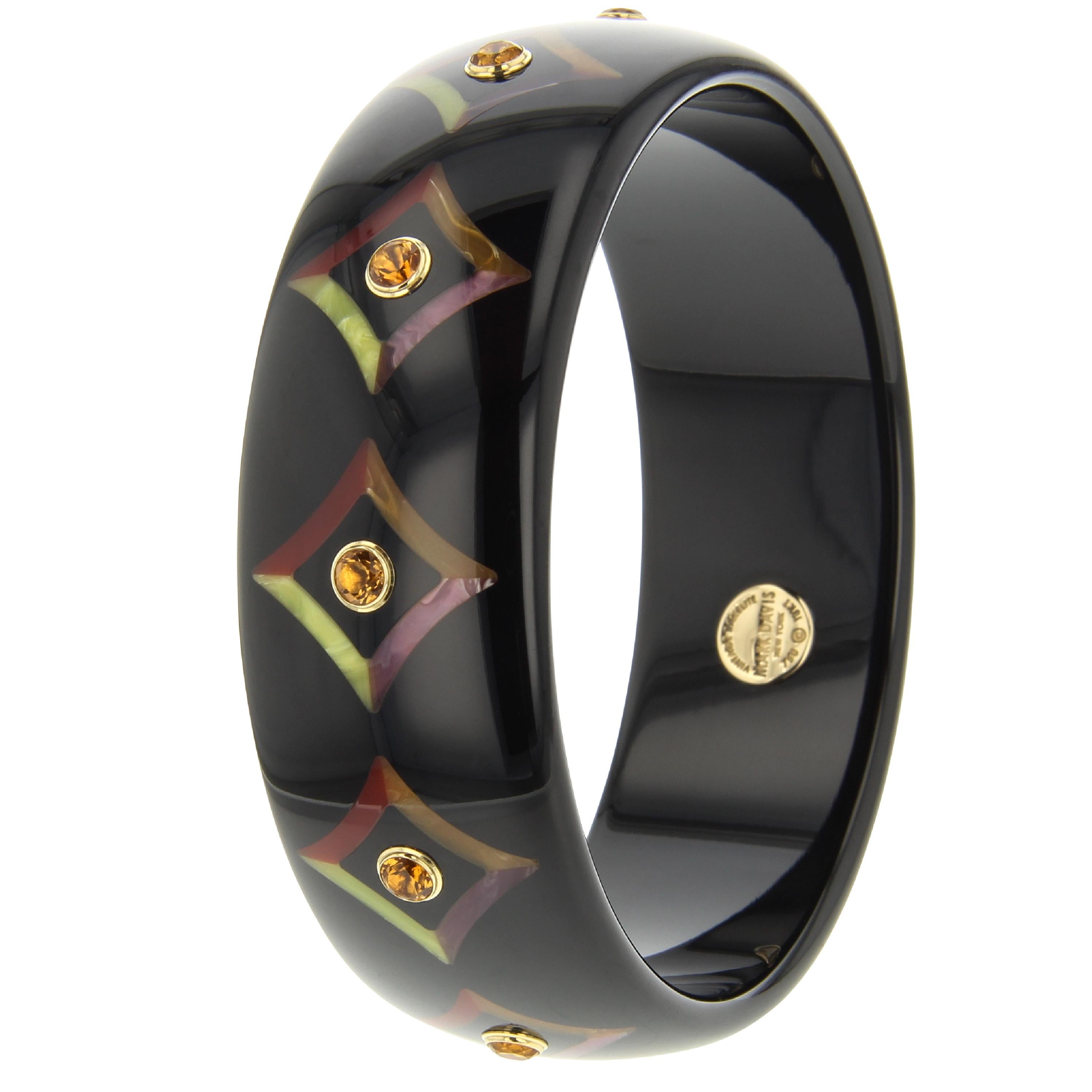 This chic and almost mysterious Mark Davis bangle was created from vintage, solid black bakelite that has been inlaid with a graphic indented diamond pattern. The inlaid pattern is created from burgundy, orange, pink and yellow bakelite. The center