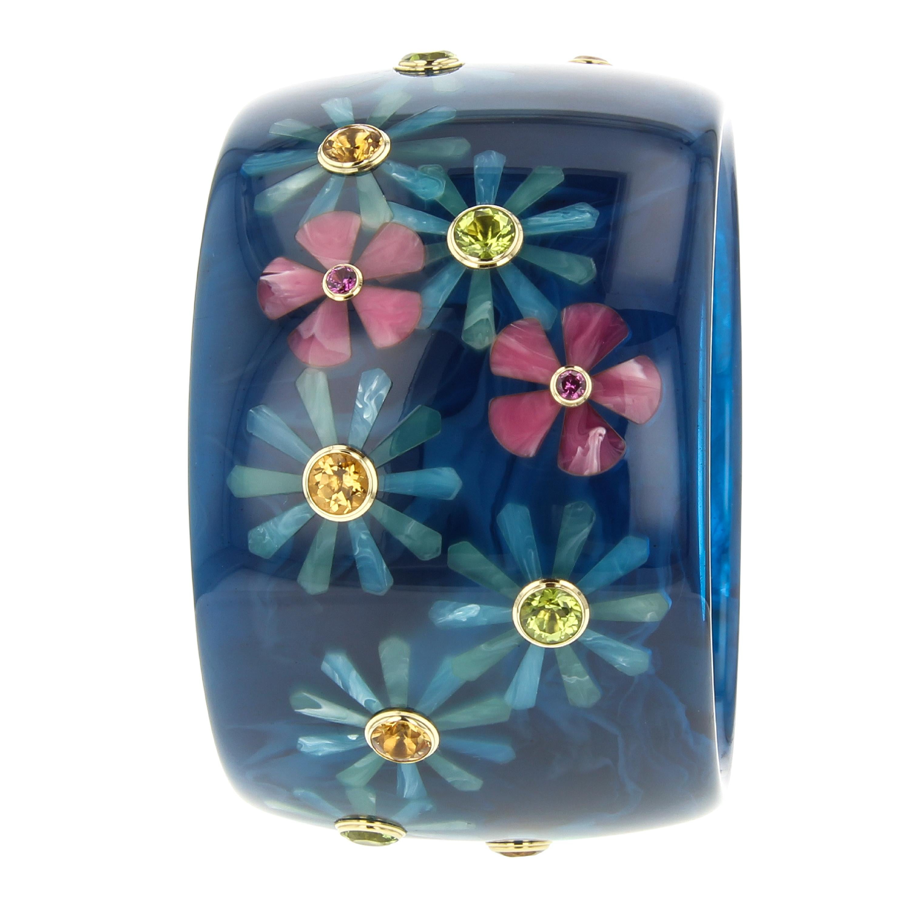 This beautiful Mark Davis bangle was created using a very subtly marbled, navy blue, vintage bakelite. A random floral pattern of greenish-blue or pink blossoms is scattered all around the bangle. The flowers are each set with a round colored