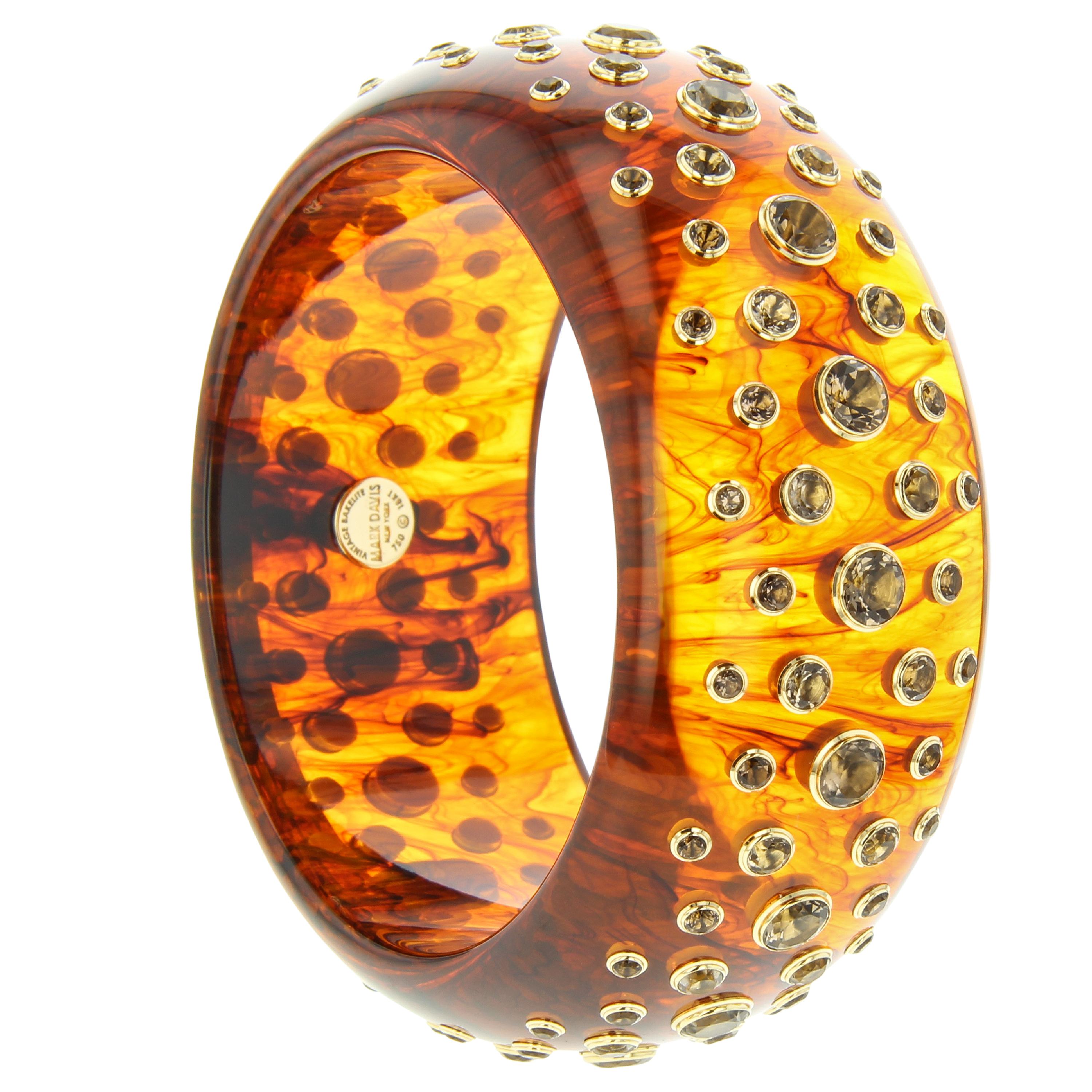 This Mark Davis bangle was handcrafted using a warm, honey-toned, tortoiseshell color vintage bakelite set with graduated smoky quartz in individual 18k yellow gold bezels.

Full details below:
• From the Mark Davis Bakelite line
• Vintage tortoise