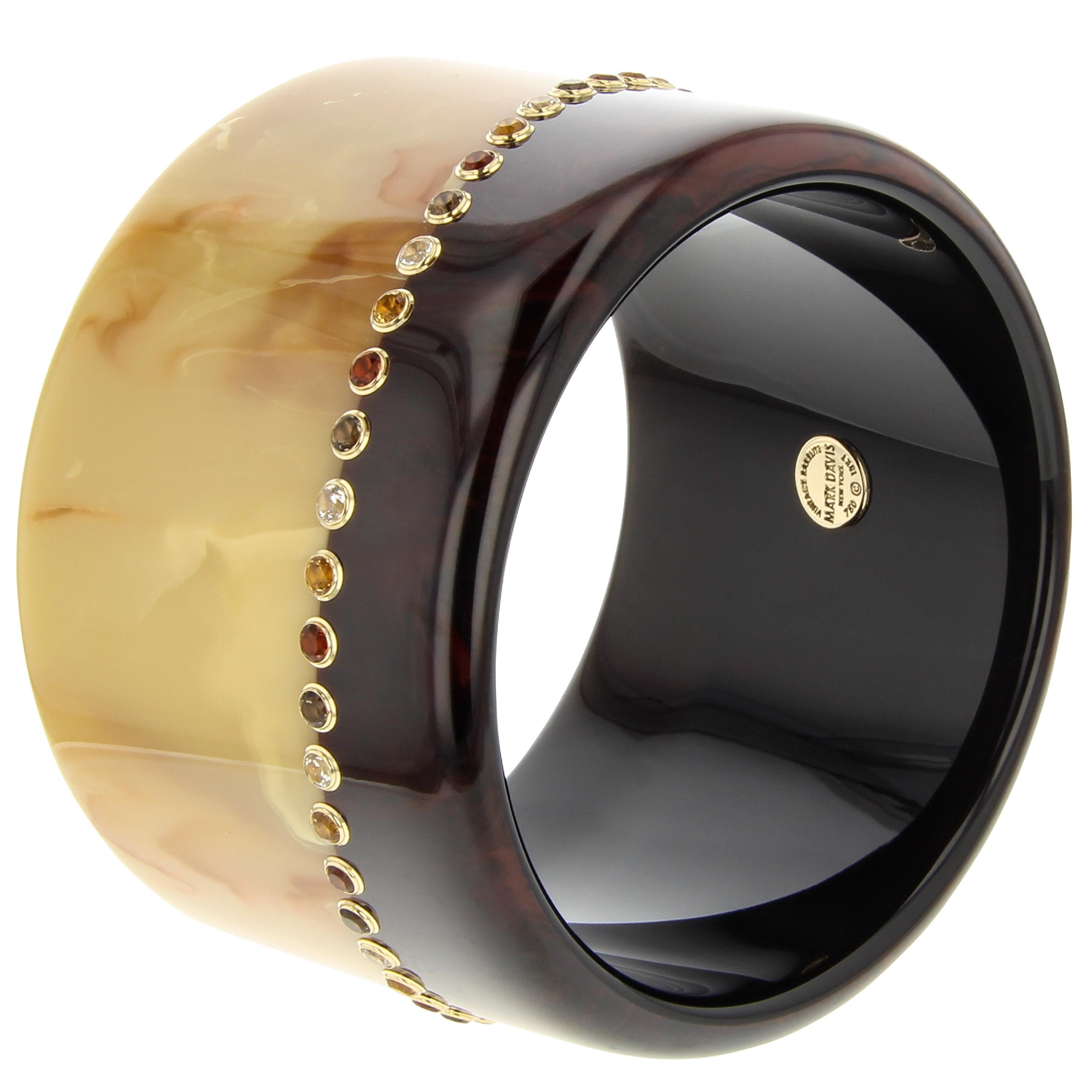 This graphic Mark Davis bangle was made with two pieces of vintage brown bakelite - one dark and one light. The two pieces have been seamlessly joined together creating an asymmetrical line that encircles the bangle. A repeating pattern of citrine,