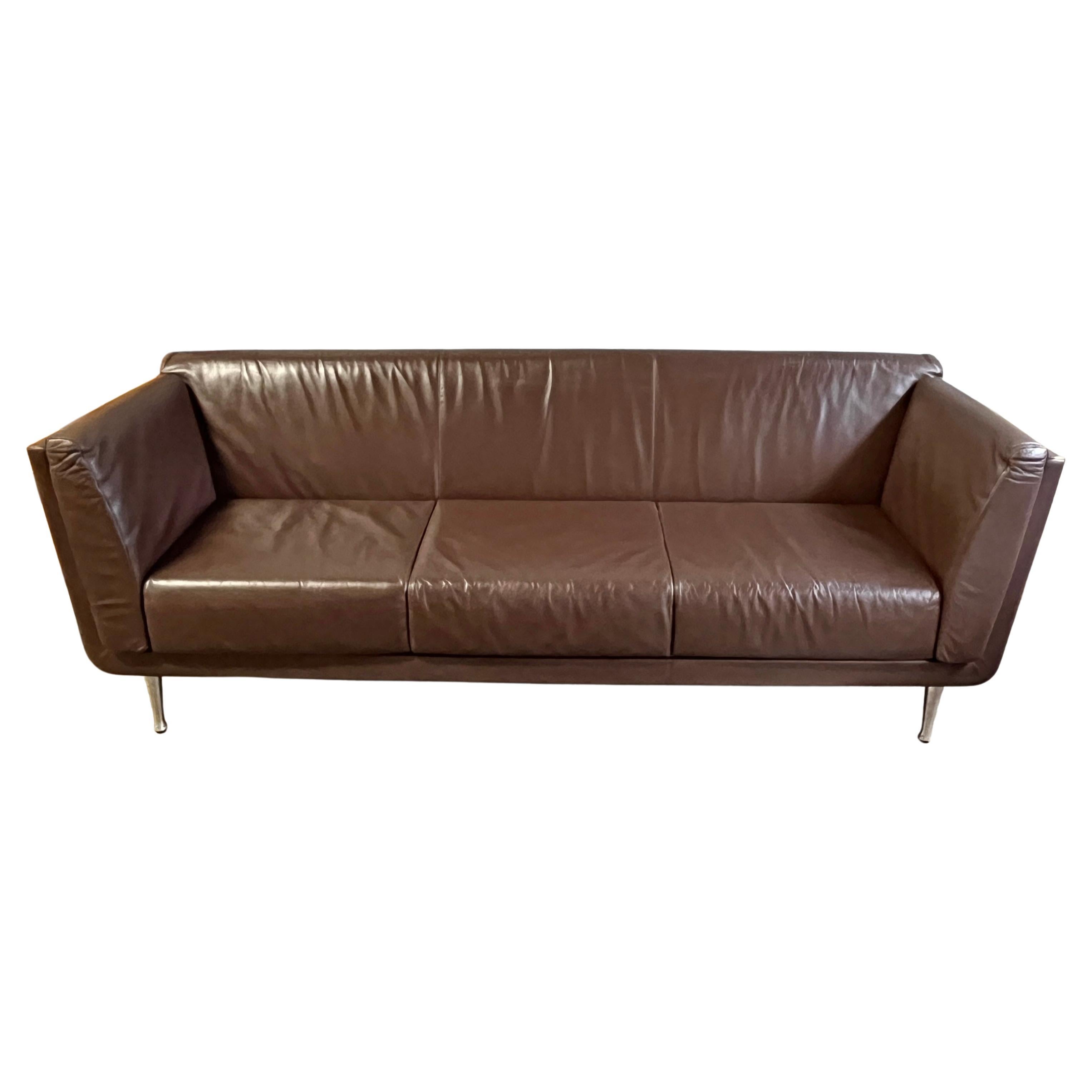 Pictures taken outside on an overcast day and inside. The color brown is more correct in the darker tone. 
This incredible 'Goetz Sofa' by Mark Goetz for Herman Miller features a walnut/cherry case, quality brown leather cushions, and aluminum legs.