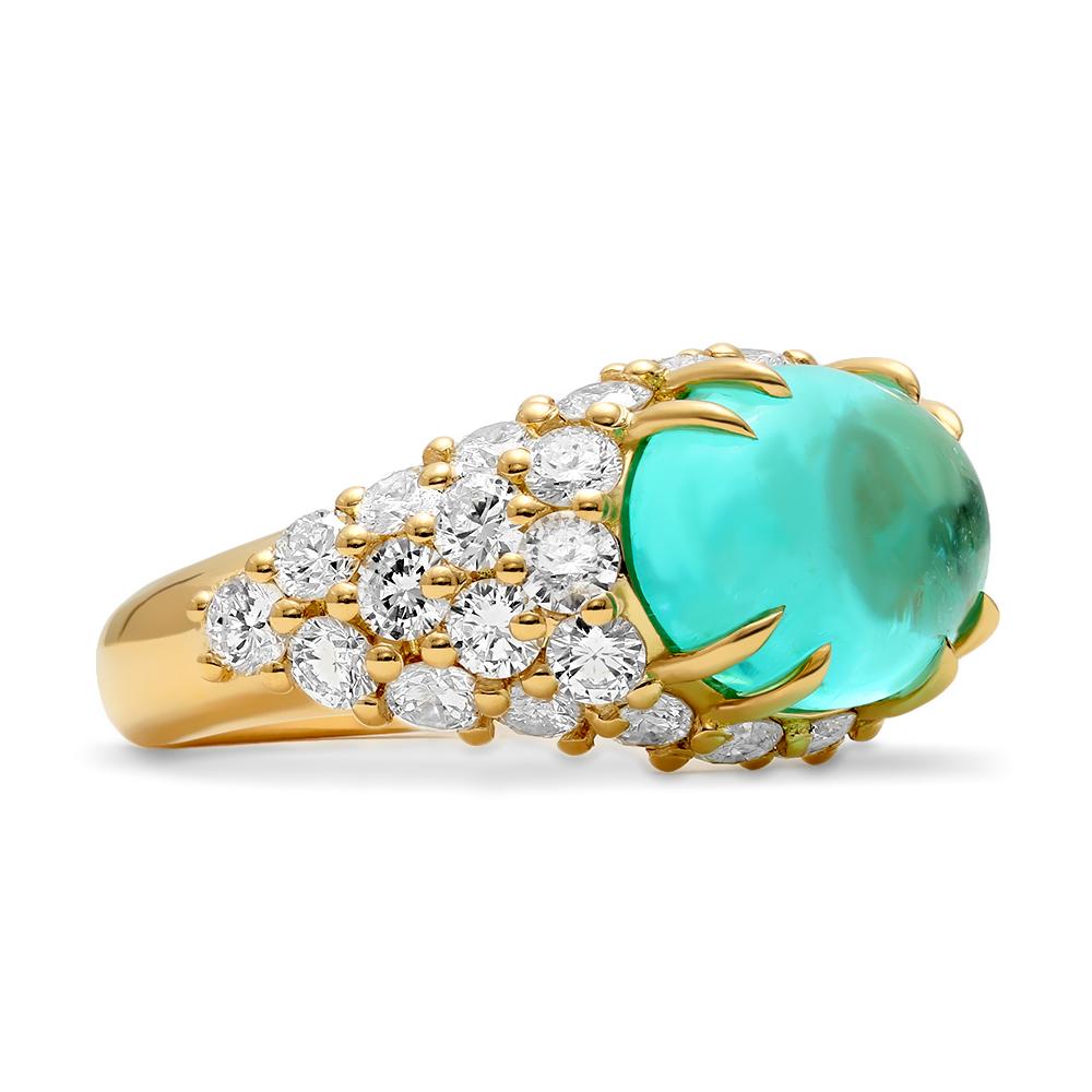 This vintage, art deco inspired cocktail ring showcases an exceedingly rare Paraiba tourmaline cabochon that is resting front and center and secured in place by pairs of claw prongs. Brilliant diamonds are set along the exteriors of the centerpiece