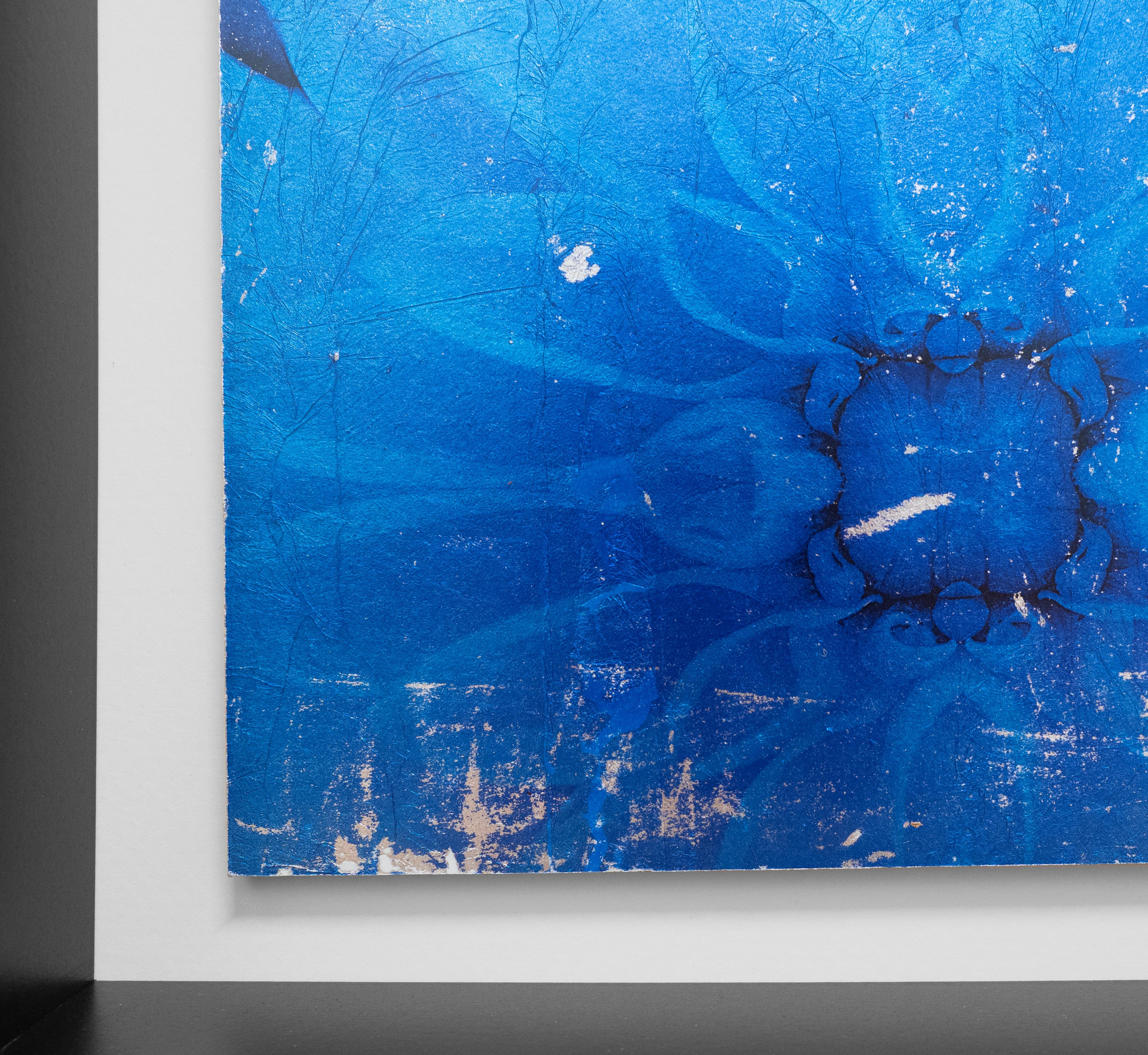 Individual 14 by Mark Jackson is a beautiful framed mixed media piece of a blue flower. Jackson prints his photographs on silver leaf and then adheres the photograph on wood panel.