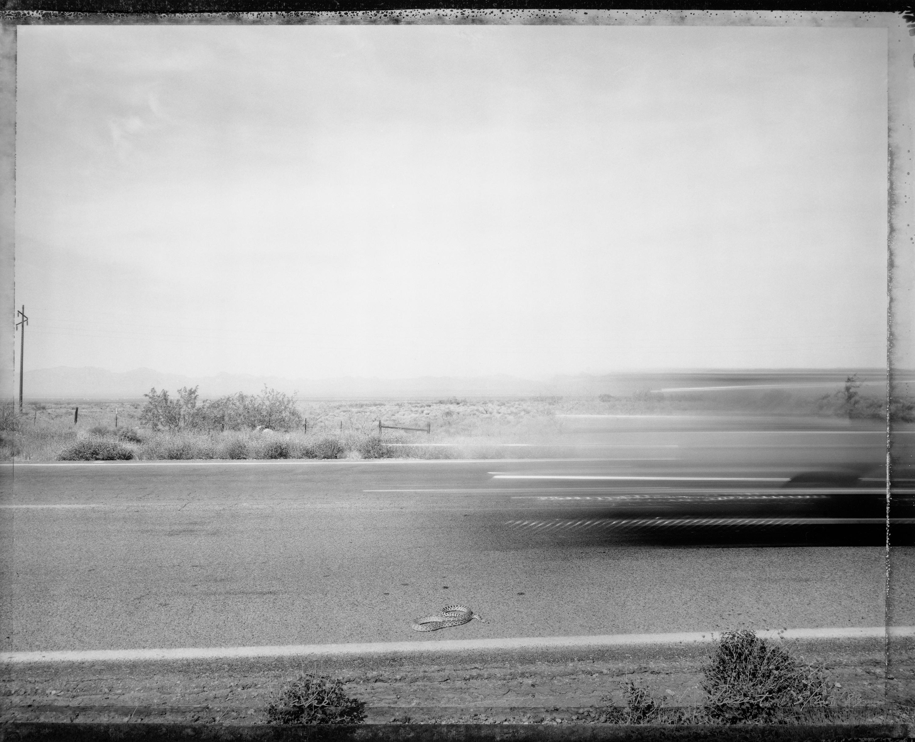 Mark Klett Black and White Photograph -  Car passing snake, Eastern Mojave Desert 