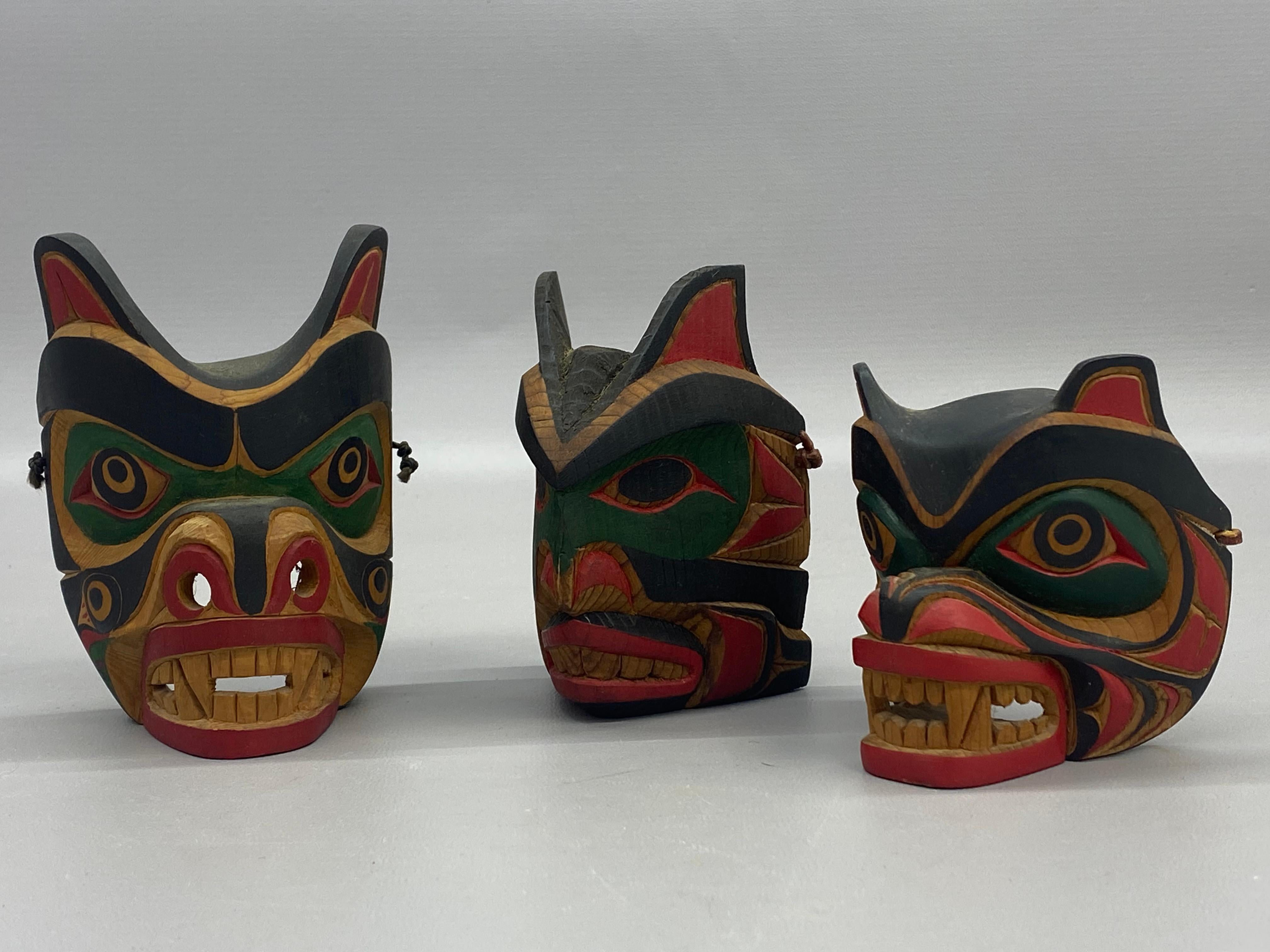 Three finely detailed hand carved and hand painted small Native American wood masks. Carved from Northern Coastal Pacific pine. All three examples are signed in pencil on the masks' interior. Circa 1980-90. 

Good overall condition with minor