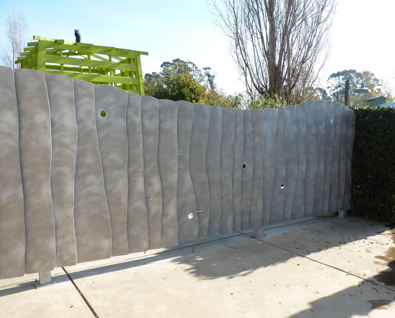 This beautifully crafted gate from California artist Mark Oldland is made from 33 uniquely curving aluminium panels, or louvers, that overlap each other at an angle to provide only a very limited view through the gate. Four vertical posts and three