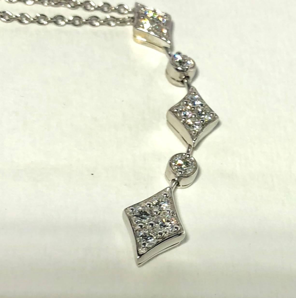 18 karat white gold diamond necklace by Mark Patterson, 14- full cut round diamonds = .77 carat total weight, average color G, average clarity SI1, pendant measures approx. 2 inches, 18 karat white gold chain measuring 17 inches, weighing 7 grams/
