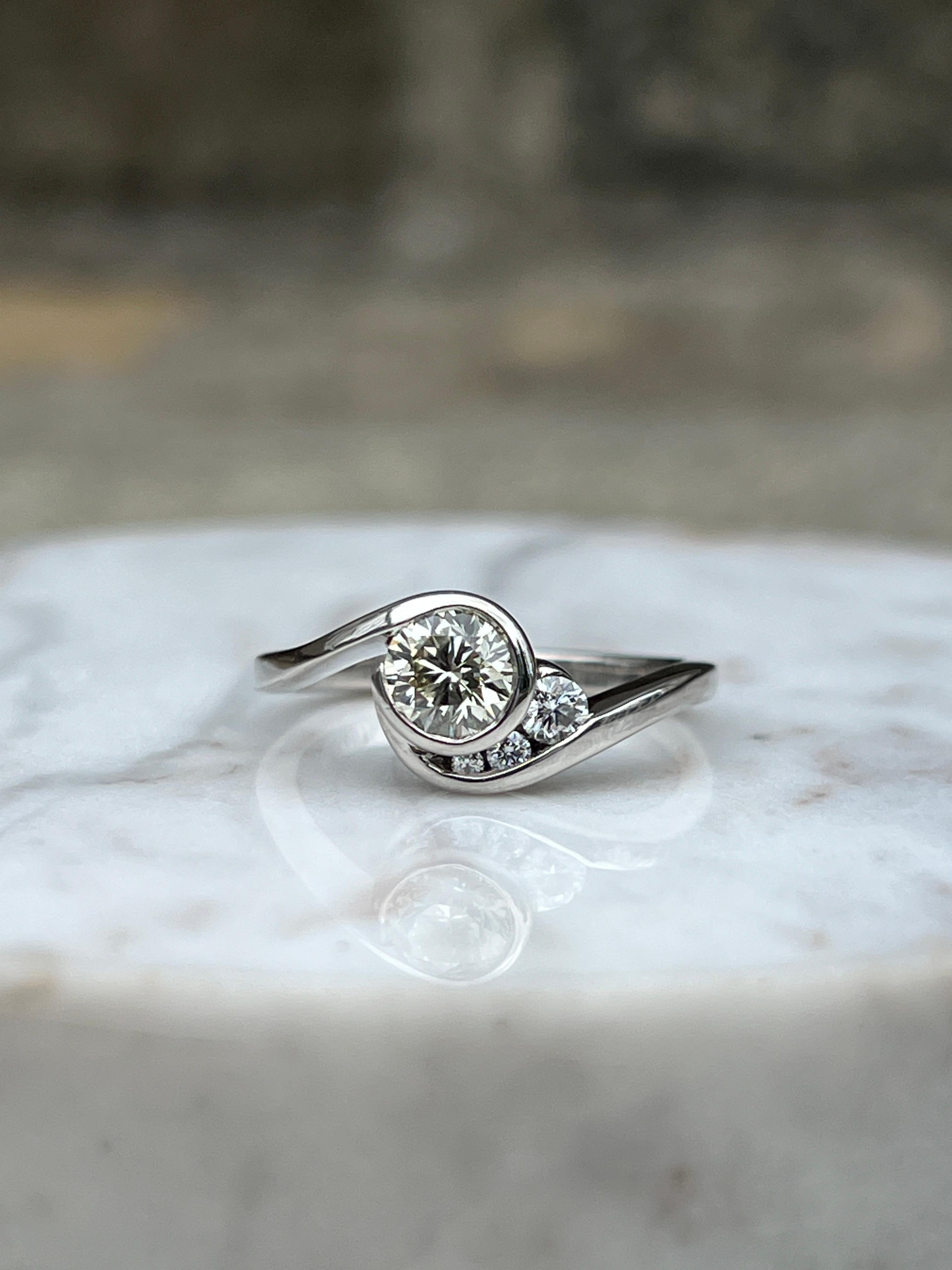 Cette bague contemporaine en palladium de Mark Schneider présente une forme libre artistique qui allie l'innovation à une brillance discrète. En son centre brille un diamant rond de taille brillant d'environ 0,65 carats, de couleur M/N et de pureté