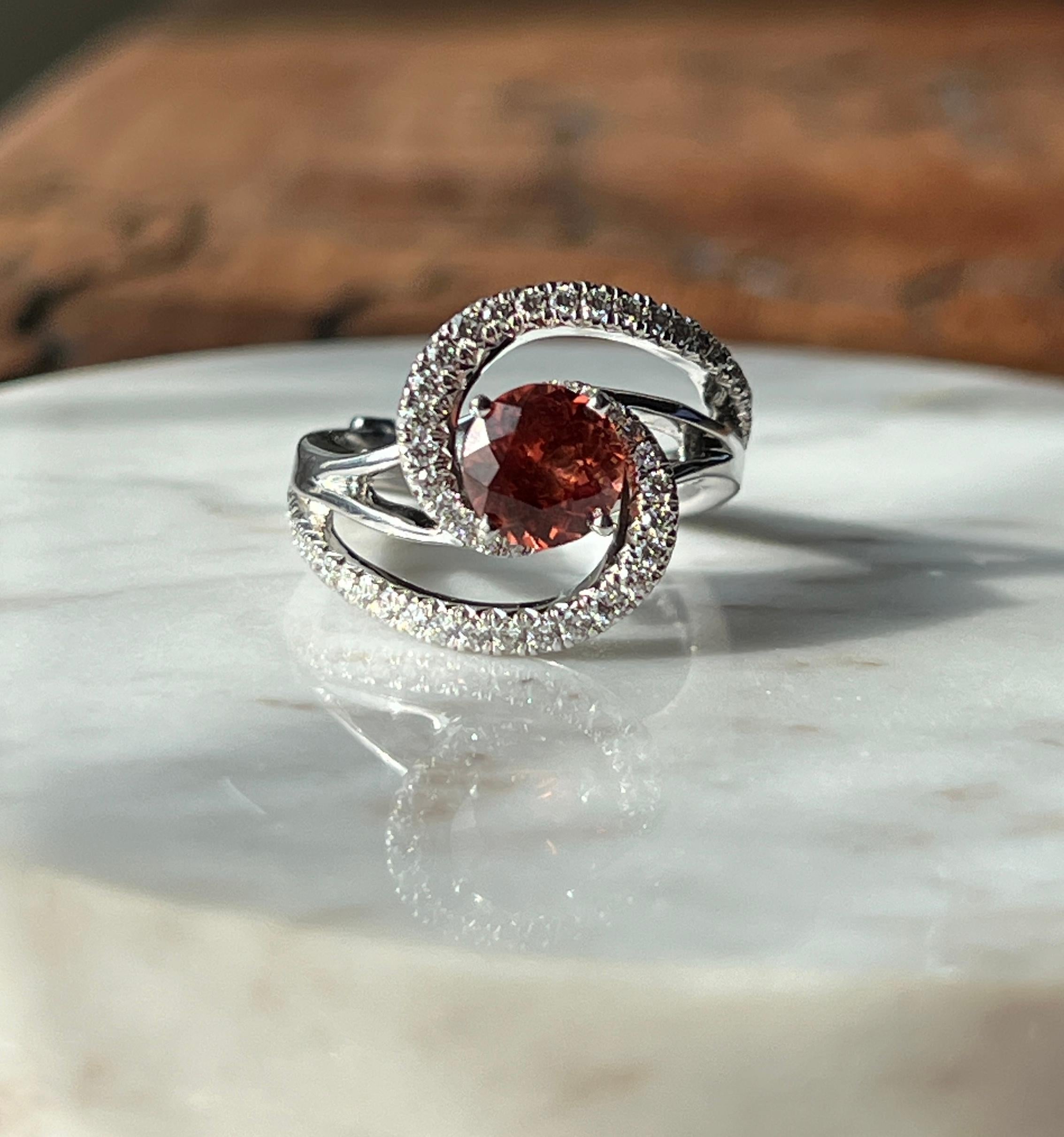 This exquisite contemporary constellation engagement ring by designer Mark Schneider is crafted in 14 karat white gold with a high-polish finish. At its center, a rich, fiery 6.85mm round brilliant spessartine garnet that commands attention. The