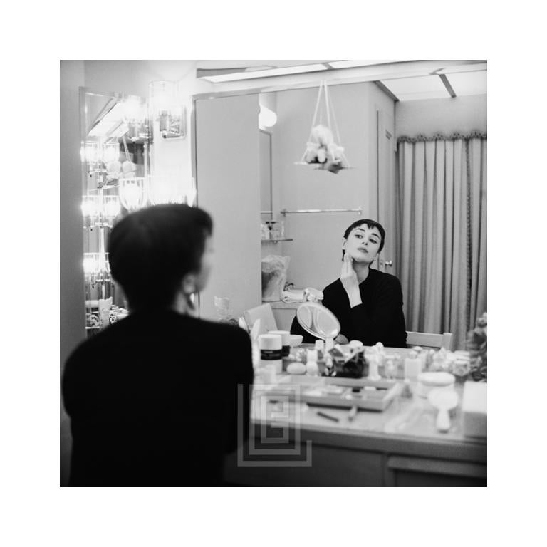 Mark Shaw Black and White Photograph – Audrey Hepburn legt Makeup in Spiegel auf, rückseitig in Ondine, 1954