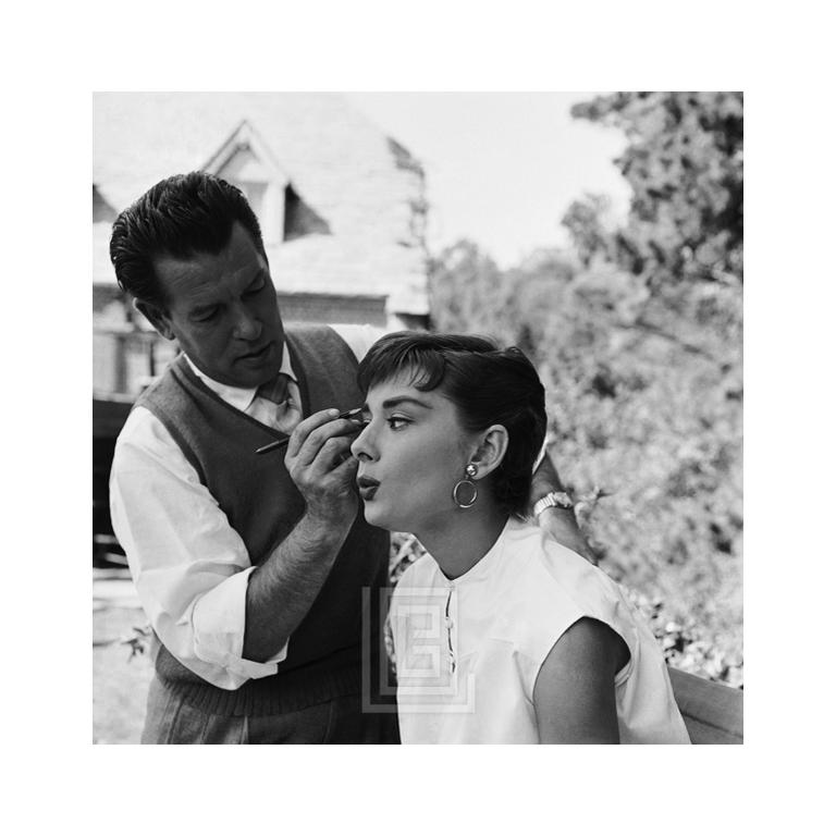 Mark Shaw Figurative Photograph - Audrey Hepburn gets a last minute touch up from Wally Westmore on the set Sabrin