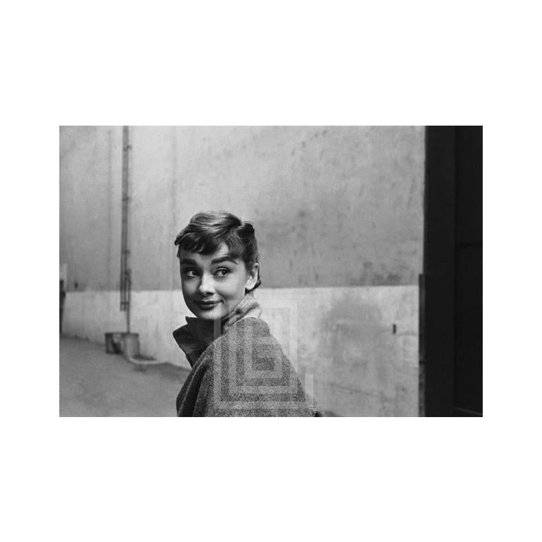 Mark Shaw Portrait Photograph - Audrey Hepburn in Grey Turtleneck Sweater, Glances Back Grinning, 1953