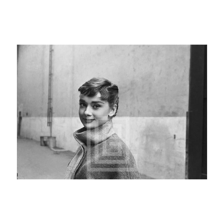Mark Shaw Portrait Photograph – Audrey Hepburn in grauem Rollkragenpullover, leuchtend links, halber Lächeln, 1953