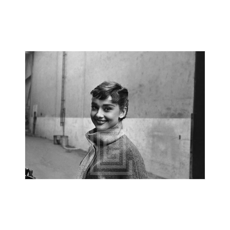 Mark Shaw Portrait Photograph – Audrey Hepburn in grauem Rollkragenpullover, leuchtend links, lächelnd, 1953