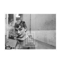 Audrey Hepburn in grauem Rollkragenpullover, leuchtend links mit Rauch, 1953