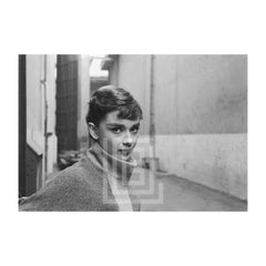 Audrey Hepburn con jersey gris de cuello alto, mirada a la derecha, barbilla hacia abajo, 1953