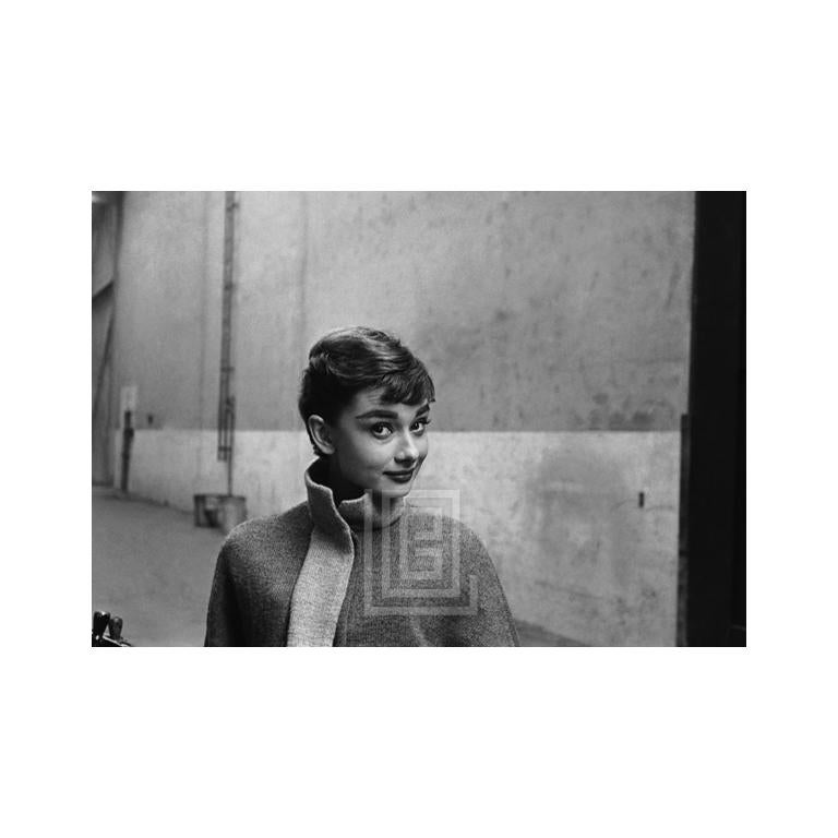 Audrey Hepburn con jersey de cuello alto gris, cabeza a la izquierda, cejas levantadas, 1953