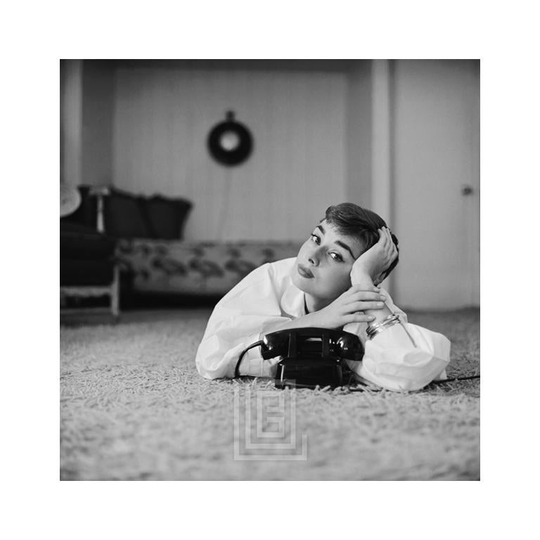 Mark Shaw Portrait Photograph – Audrey Hepburn in weißer Bluse mit Telefon, Kopf auf der Hand, gekippt, 1953