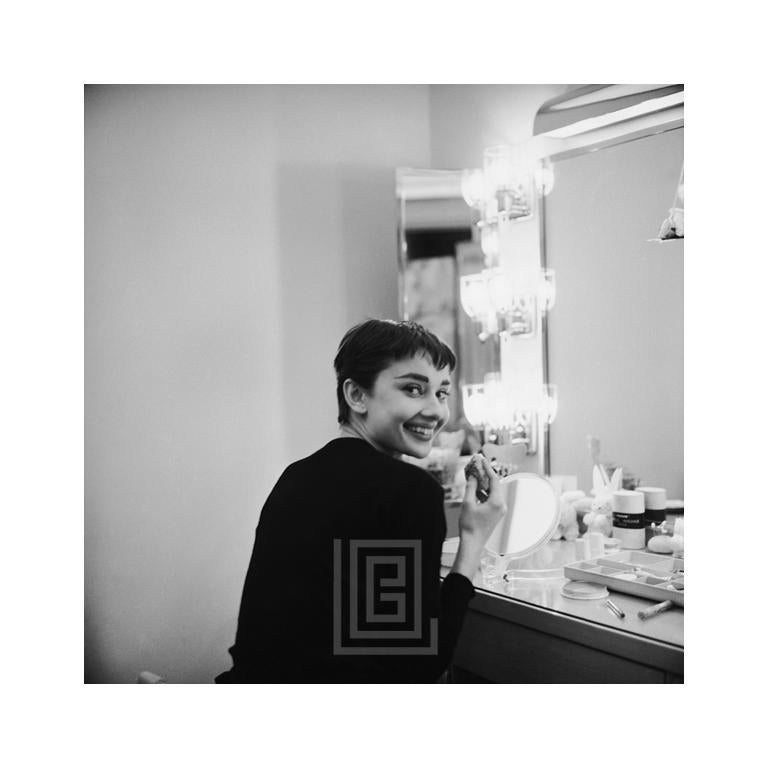 Black and White Photograph di Mark Shaw - Audrey Hepburn si guarda indietro sorridendo, nel backstage di Ondine, 1954