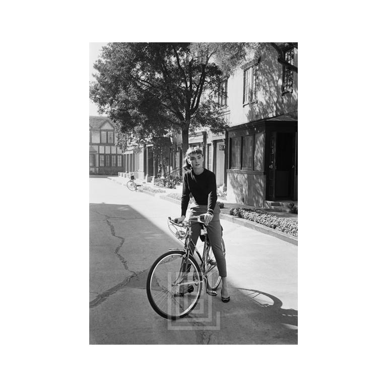 Mark Shaw Figurative Photograph – Audrey Hepburn auf Fahrrad, blickend nach links, 1953