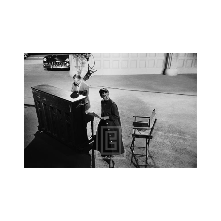 Black and White Photograph Mark Shaw - Audrey Hepburn sur le tournage de Sabrina, près du piano, 1953