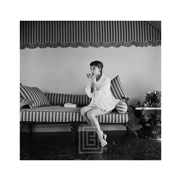 Portrait Photograph Mark Shaw - Audrey Hepburn sur canapé rayé, applique du rouge à lèvres, 1954