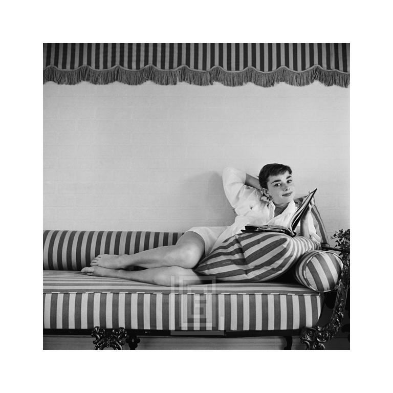 Mark Shaw Black and White Photograph – Audrey Hepburn auf gestreiftem Sofa, Rückenlehne mit Klappdeckel, Kopffliesen, 1954