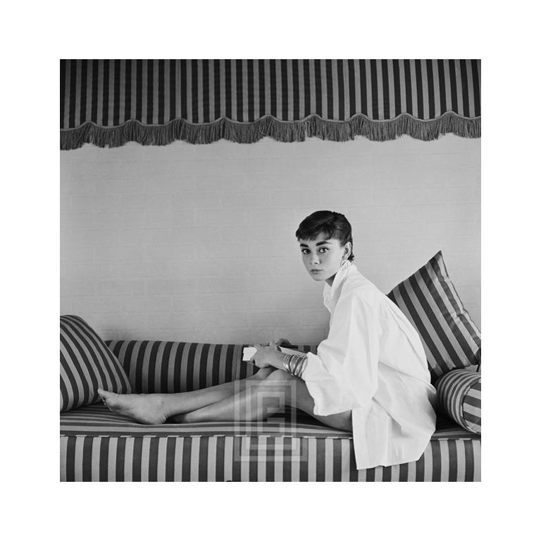 Black and White Photograph Mark Shaw - Audrey Hepburn sur canapé rayé, Leans Forward, 1954