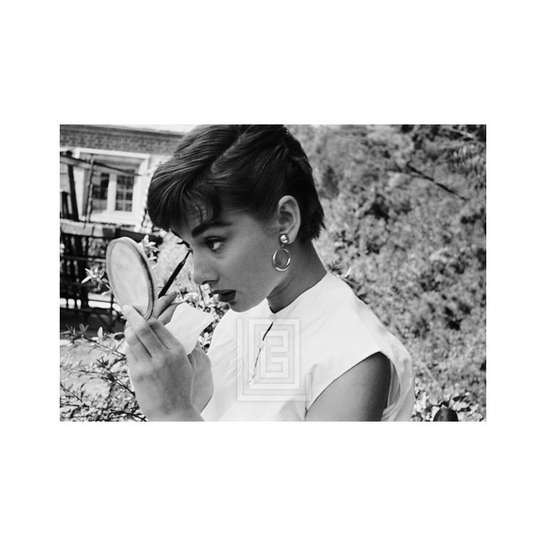 Portrait Photograph Mark Shaw - Audrey Hepburn mettant sur le maquillage dans un miroir, 1953