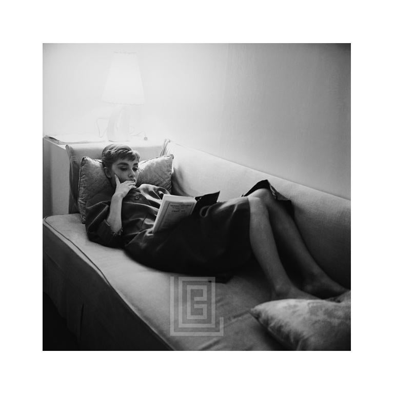 Mark Shaw Black and White Photograph - Audrey Hepburn Supine Reading on Couch, 1953