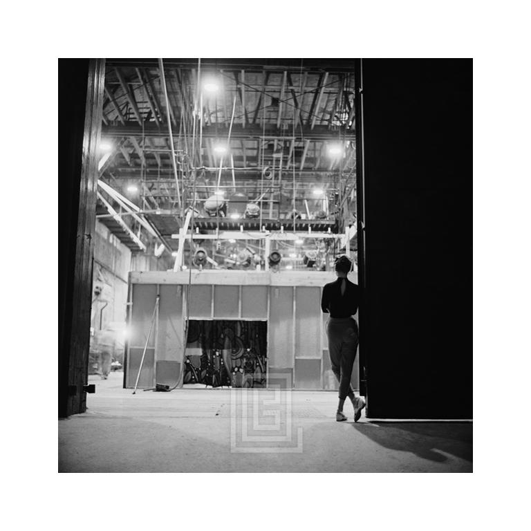 Mark Shaw Figurative Photograph - Audrey Hepburn viewing the soundstage of Sabrina, 1953