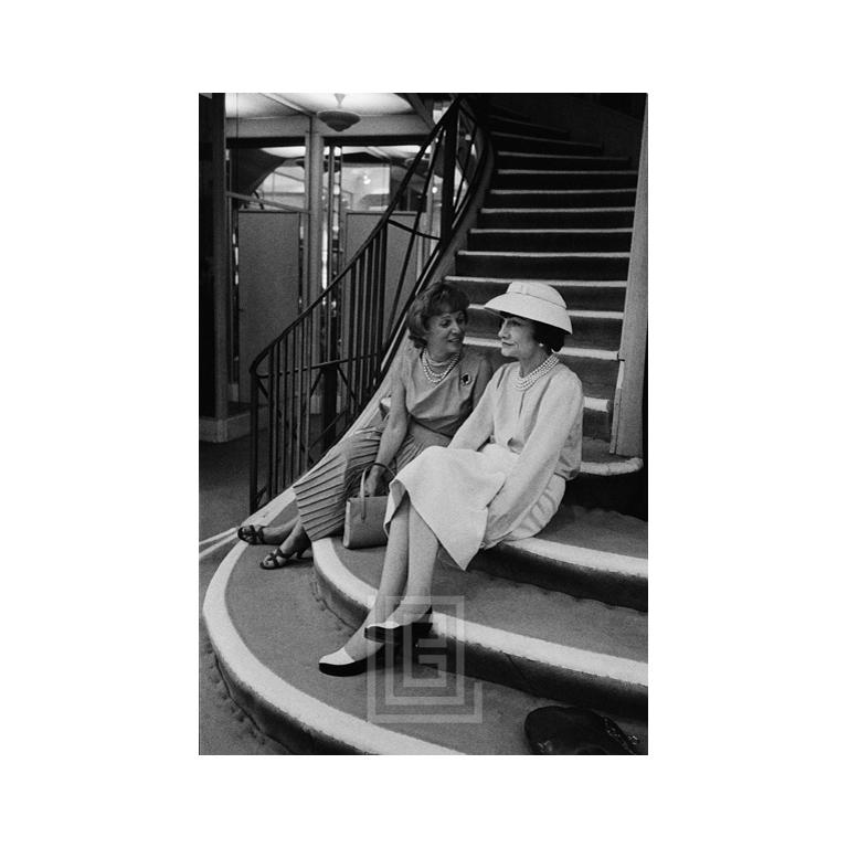 Mark Shaw Black and White Photograph - Coco Chanel Sits on Stairs with Unidentified Woman, 1957
