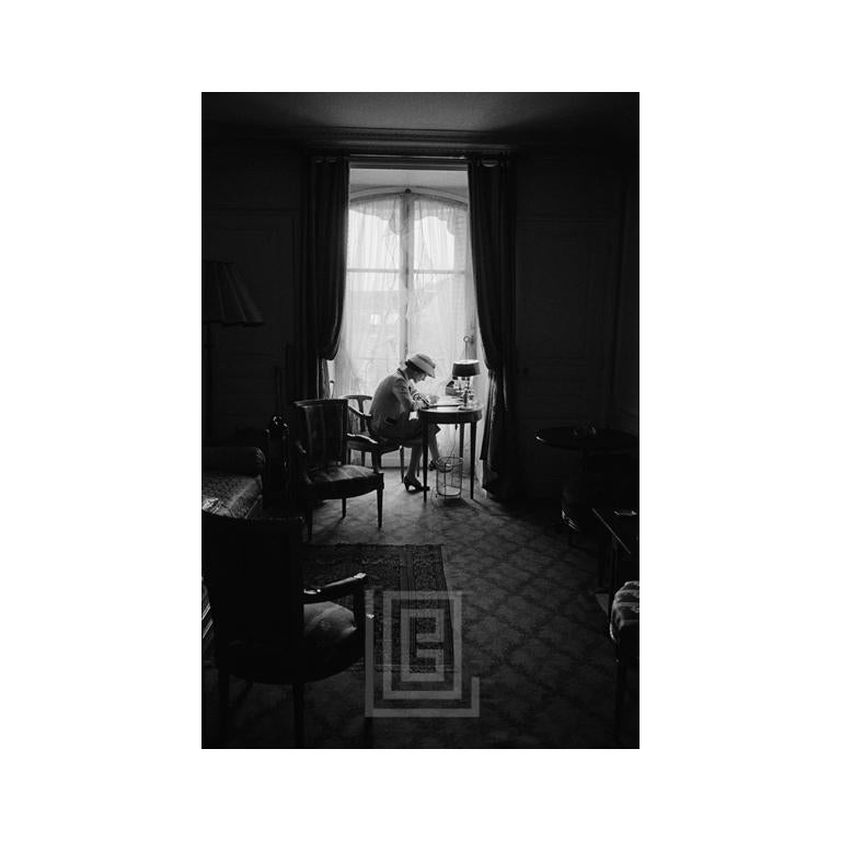 Coco Chanel Writes at Desk in Window, Head Down, 1957