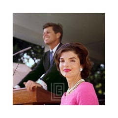 Kennedy, Jackie con vestido rosa, John en el podio