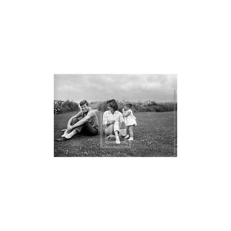 Black and White Photograph di Mark Shaw - John Kennedy, Hyannis Beach, John che sorride, Jackie e Caroline guardano John, 1959
