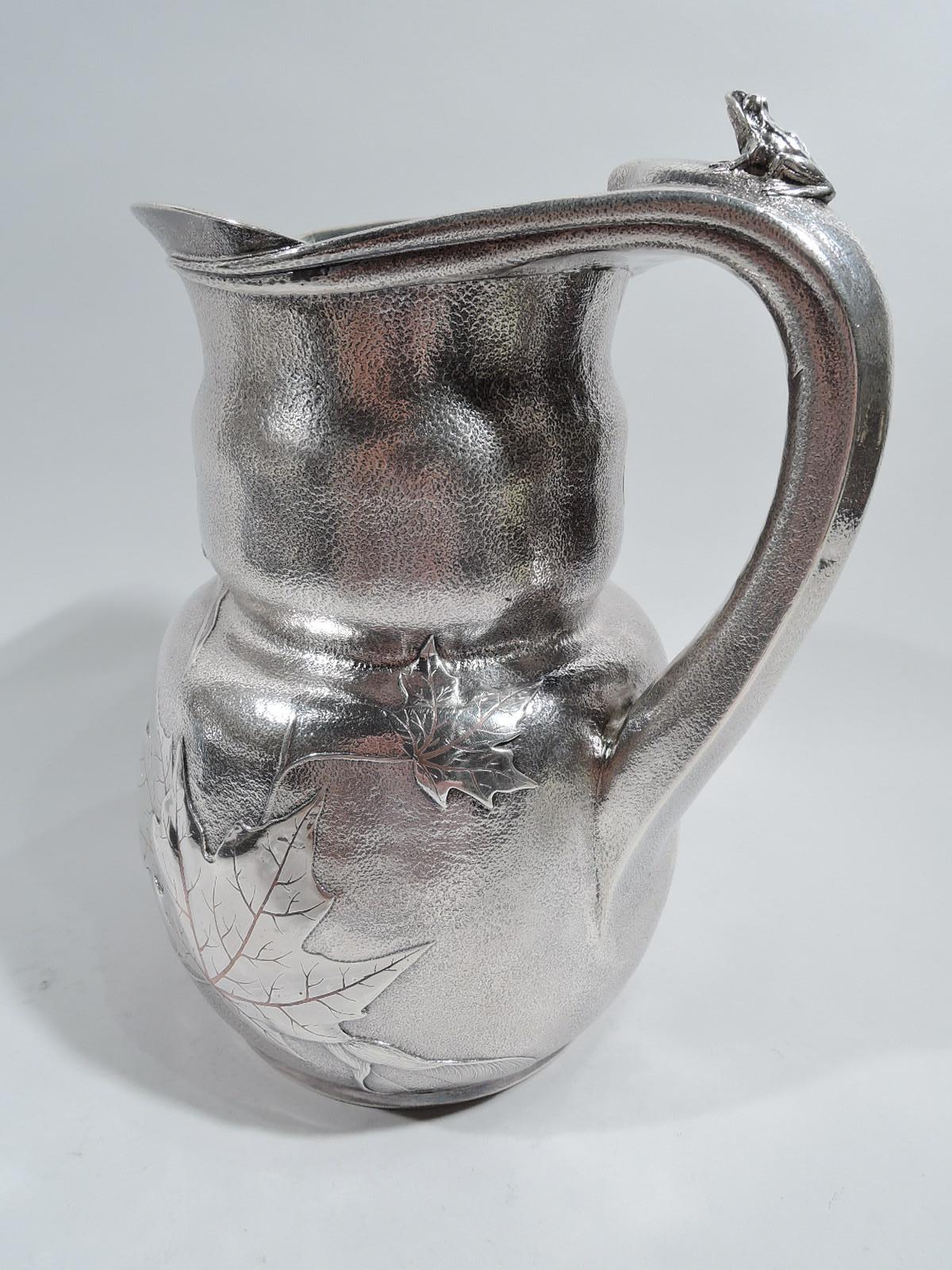Market-fresh Japonesque mixed metal and sterling silver water pitcher. Made by Tiffany & Co. in New York. Gently curved bowl and inset undulating rim with wide lip spout and integral scroll handle with tendril mounts that wraparound mouth rim.