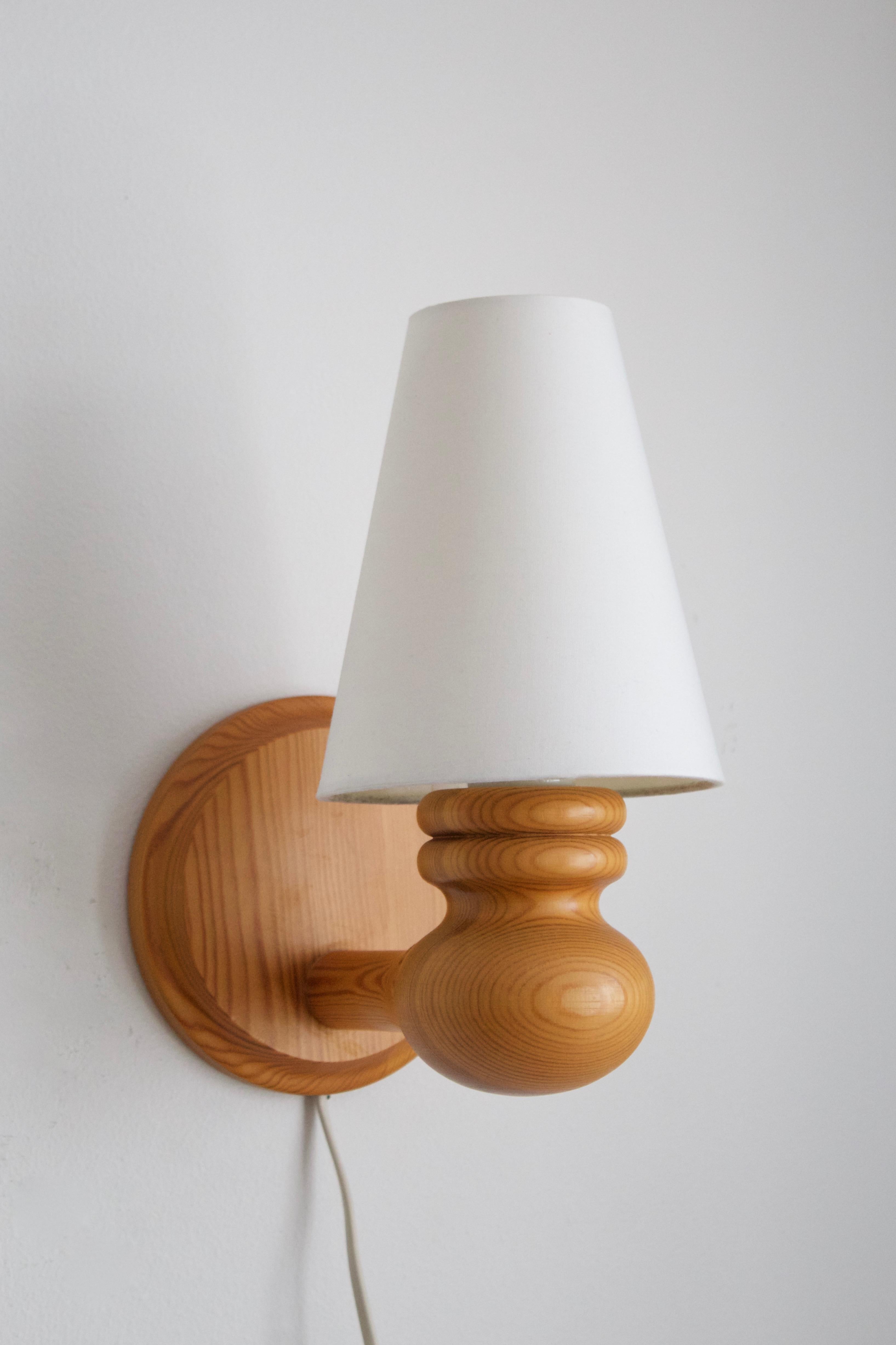 A pair of wall lights. In solid pine. Brand new lampshades. Produced by Markslöjd, Kinna, Sweden, c. 1970s. Marked 

Stated dimensions include lampshade. 

Diameter of backplate, 15 cm.