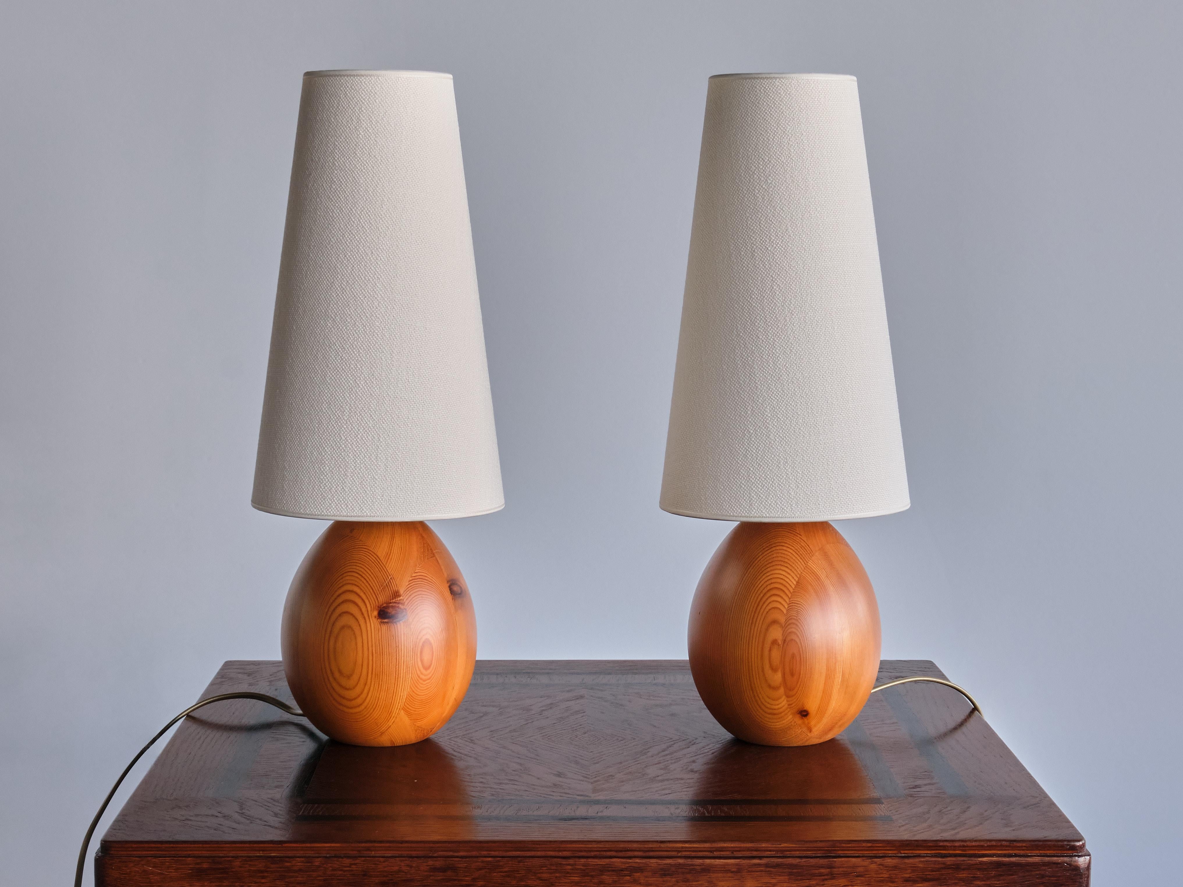 This striking pair of table lamps was produced by the manufacturer Markslöjd in Sweden in the 1960s.
The organic, oval shaped bases are made of solid pine wood with a beautiful wood grain. The tall, cone shaped shade gives the design a striking