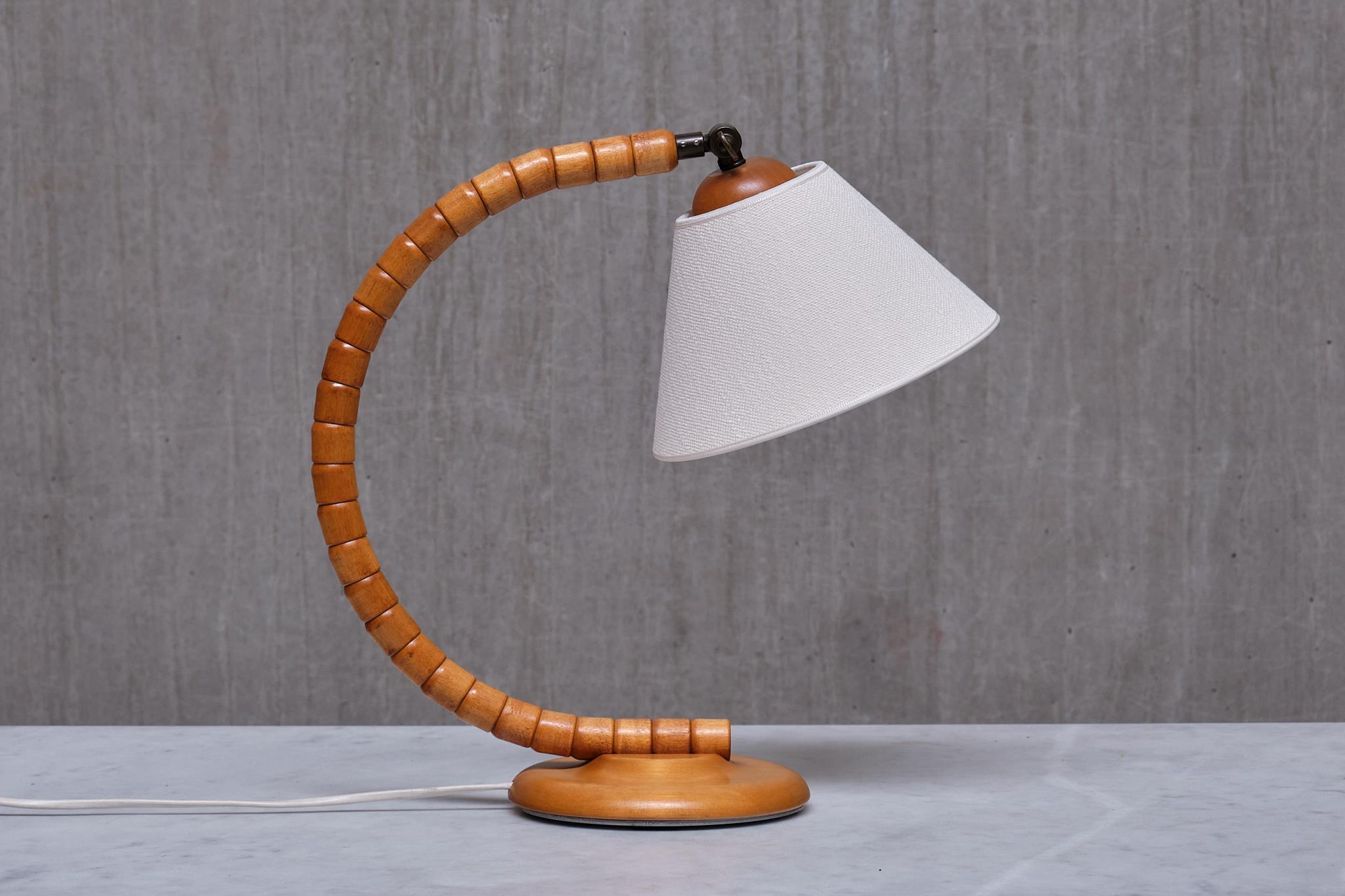 This striking table lamp was produced by Markslöjd in Kinna, Sweden in the 1960s. 

The design is marked by the sculptural, organic shaped frame resting on a circular base. The base is made of solid stained beech wood. Brass fitting, and Markslöjd