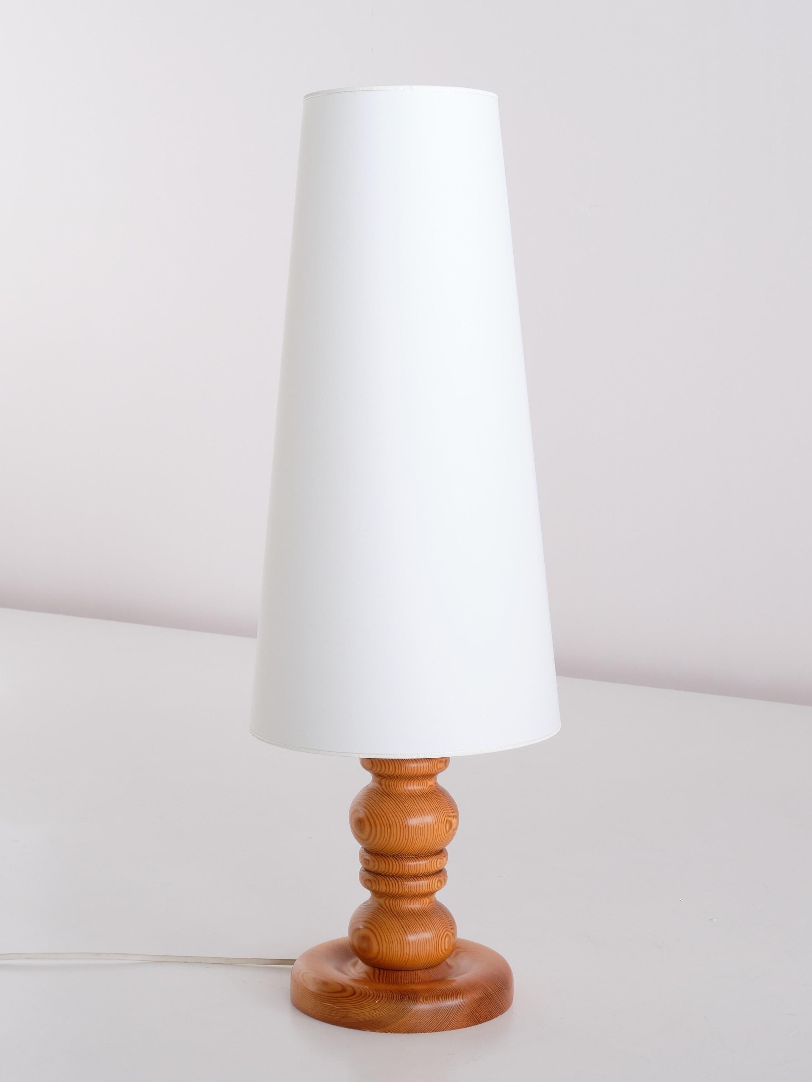 This table lamp was produced by Markslöjd in Kinna, Sweden, in the early 1970s. The base is in solid pine with a beautiful wood grain. The tall, cone shaped shade gives the design a striking appearance. The custom shade is newly made in an ivory