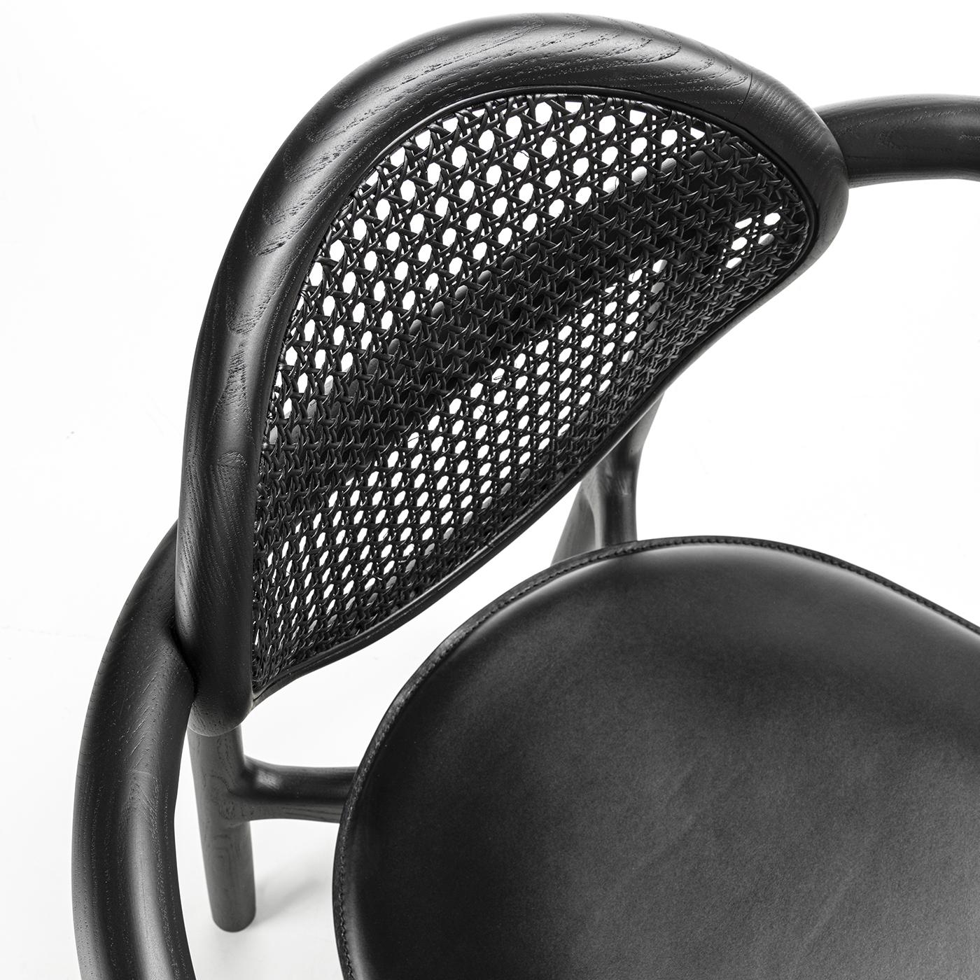 Marlena est un fauteuil extrêmement élégant avec une structure en bois massif à sections irrégulières disponible en frêne ou en noyer Canaletto. Le dossier en paille de Wien est disponible en naturel ou en noir. Le siège est recouvert de différents