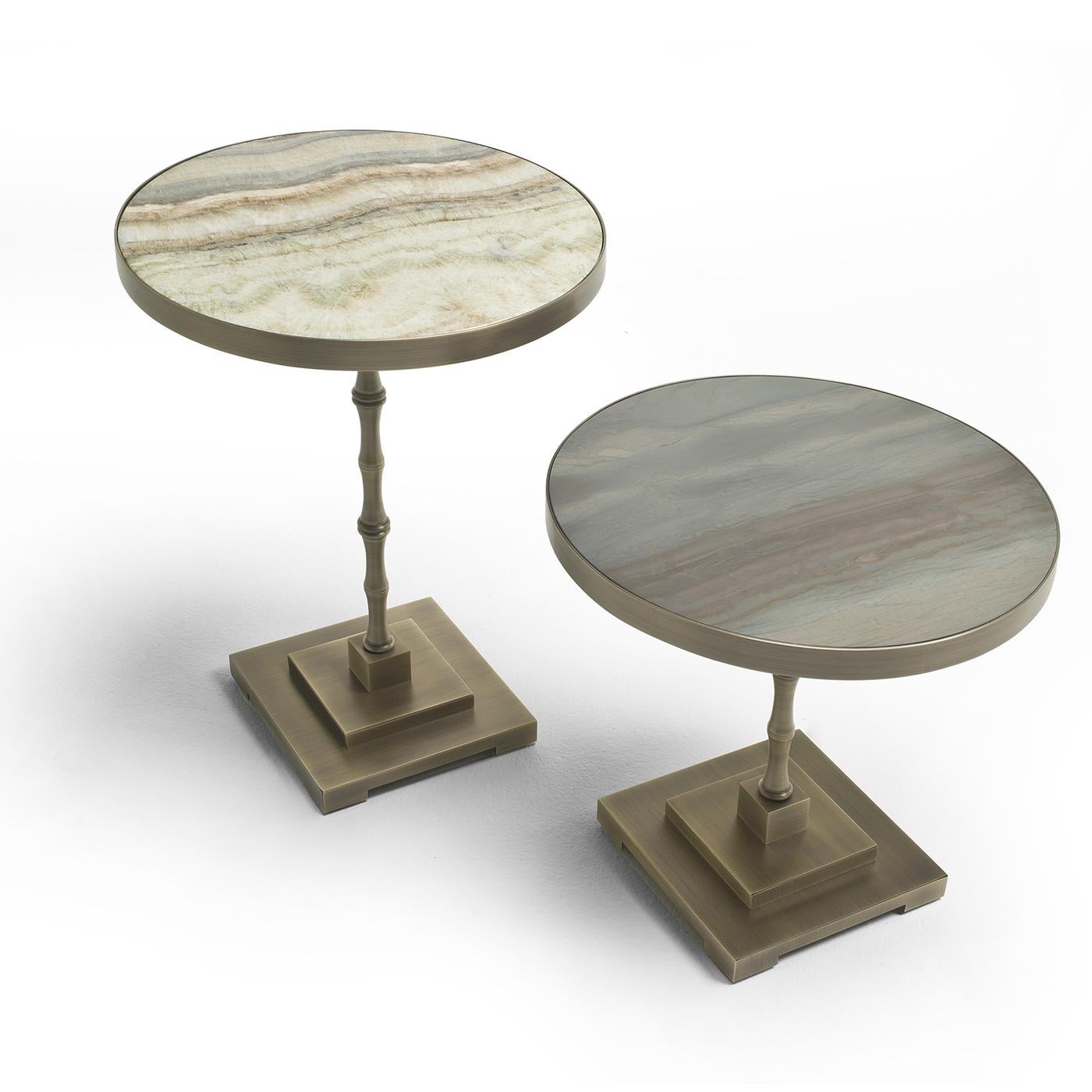 Der Marmora Beistelltisch vereint eine ganze Reihe von Inspirationen in sich. Auf einem gestapelten quadratischen Sockel steht der Tisch auf einem bambusähnlichen Stiel und ist mit einer runden Fläche versehen. Die Tischplatte ist aus Onice-Marmor