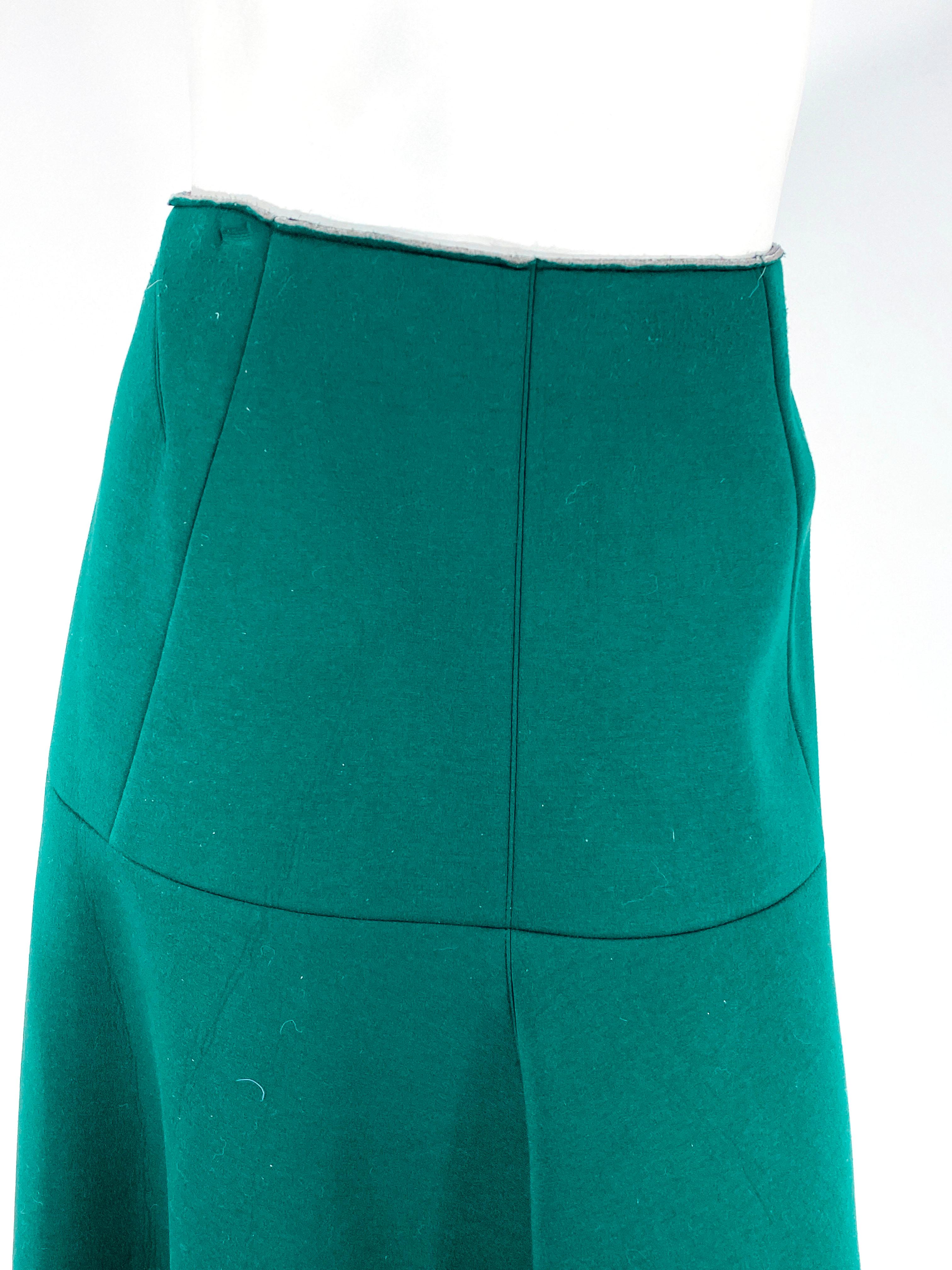 Marni hunter green scuba skirt with a fitted silhouette past the hip going to a full A-line that reaches a traditional tea-length. The hem and the waist band are unfinished with raw cut edges. 