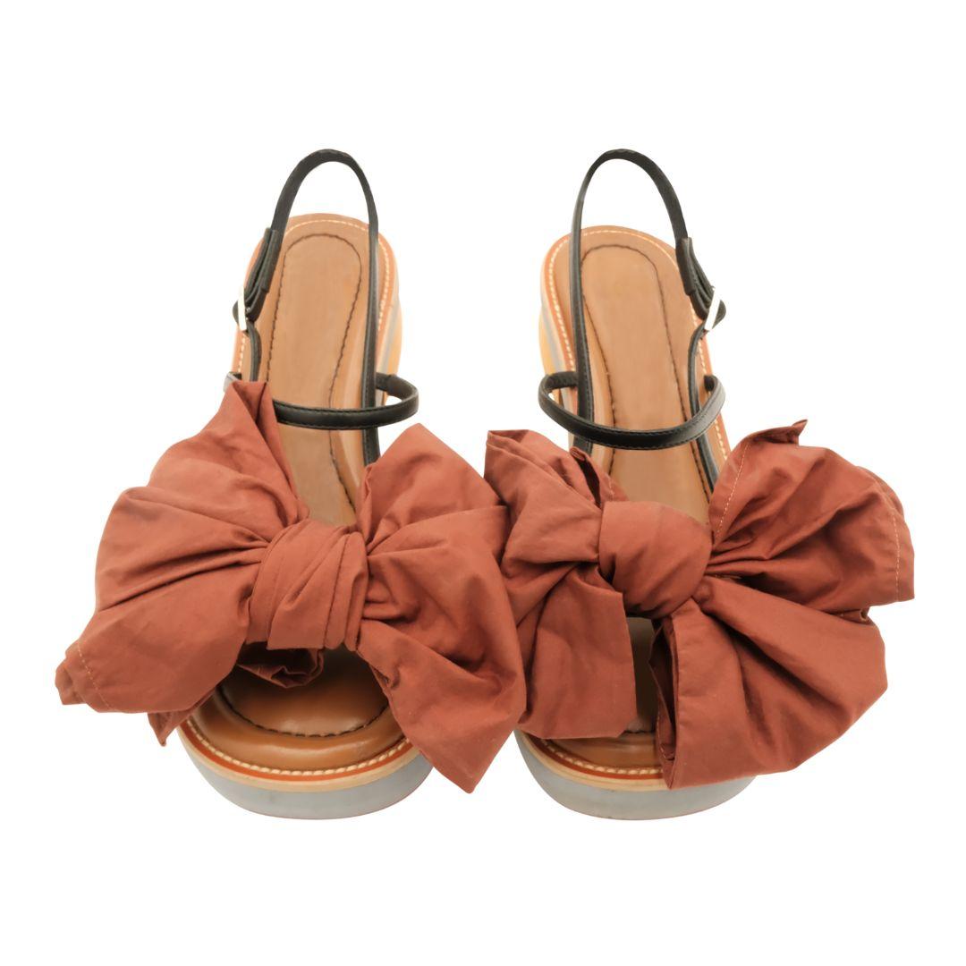 Marni large brown bow sandals with black leather ankle straps.

Wooden heel and gray foam platform soles.

Padded leather upper soles provide additional comfort.

Cotton bows can be untied and detached for easy cleaning.

Condition Details: In very
