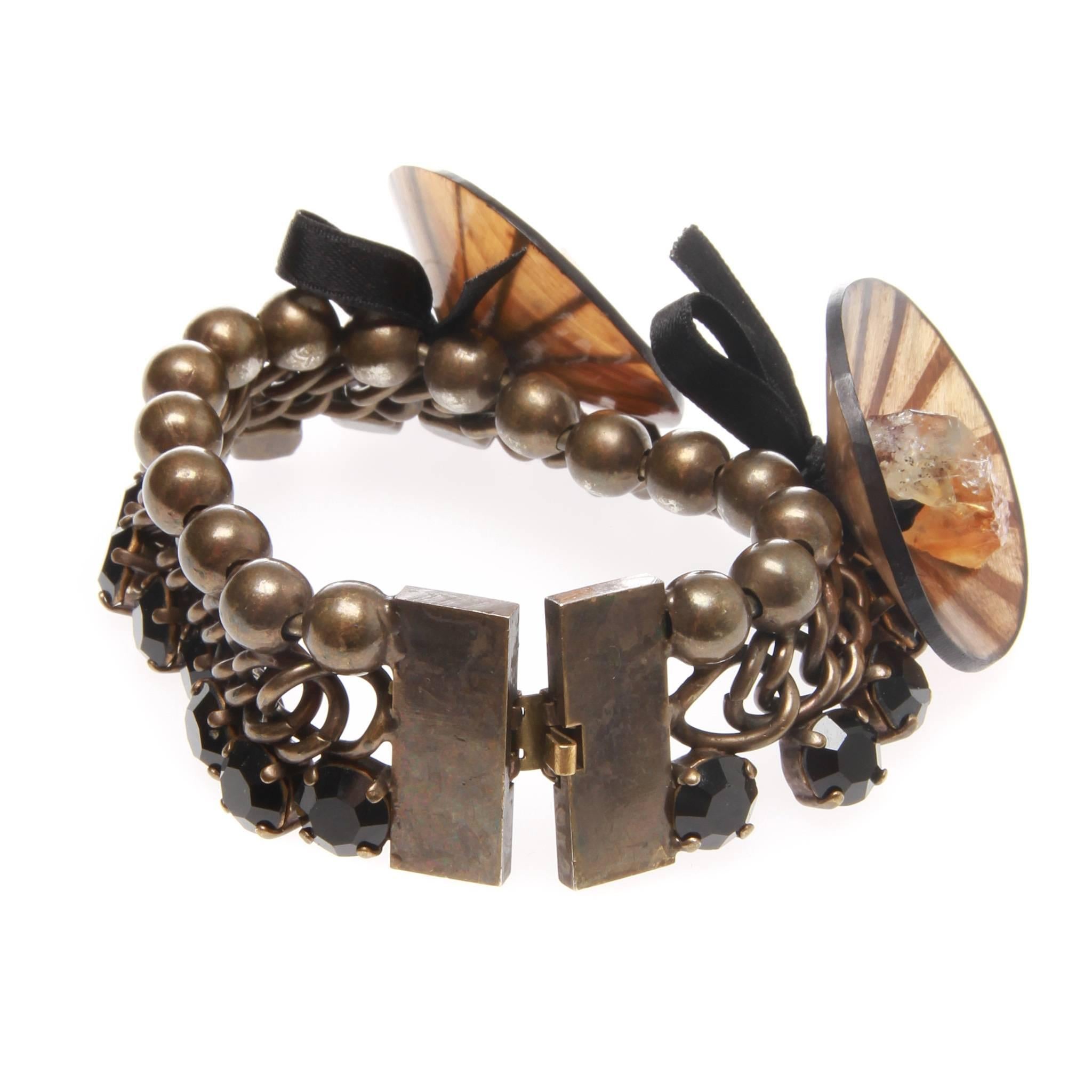 A beautiful MARNI Pyrite-embellished flower bracelet.

Marni brooch has a ball-trimmed chain, black Swarovski crystal embellishment, ribbon bows beneath flowers and a push-lock clasp to fasten to wrist.
Light-brown and black floral horn flower