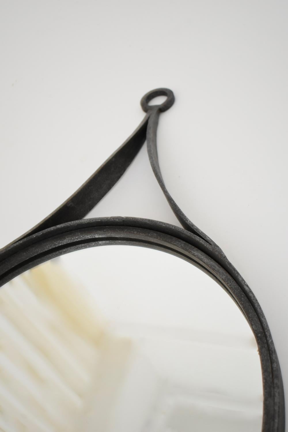 Circular round brutalist mirror in wrought iron supported by a handle, in the style of the Ateliers de Marolles. France, 1960s.